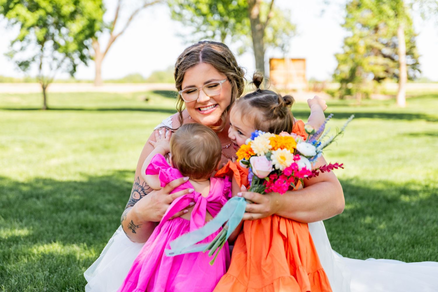 Colorful floral arrangements and bright dresses create a cheerful wedding celebration atmosphere outdoors.
