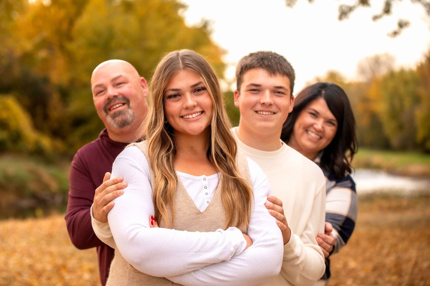 A playful family portrait outdoors with golden autumn foliage in the background by the Chippewa River