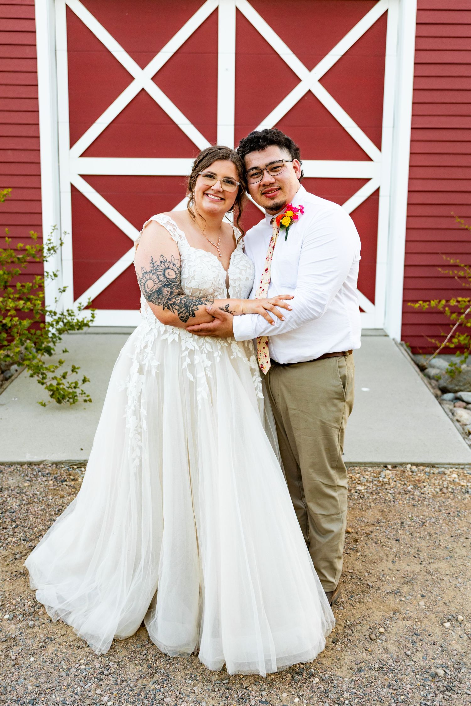 Newlyweds pose together in front of a red and white barn door.