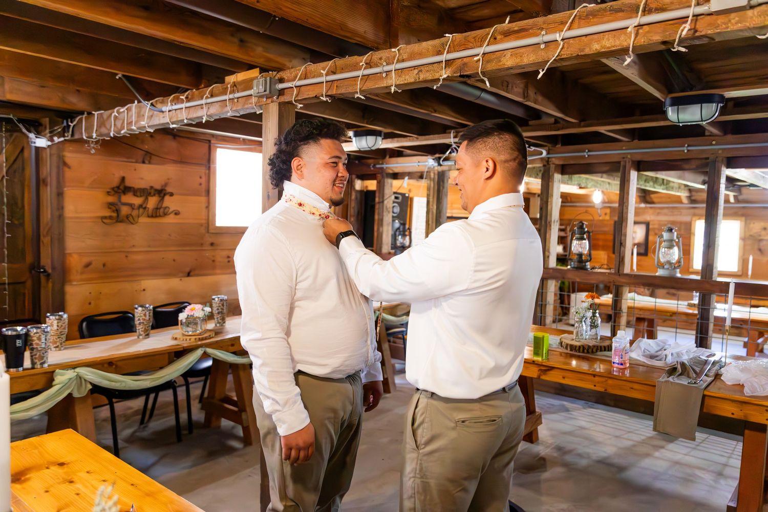 Rustic barn interior with wooden beams and industrial lighting for a wedding reception venue.