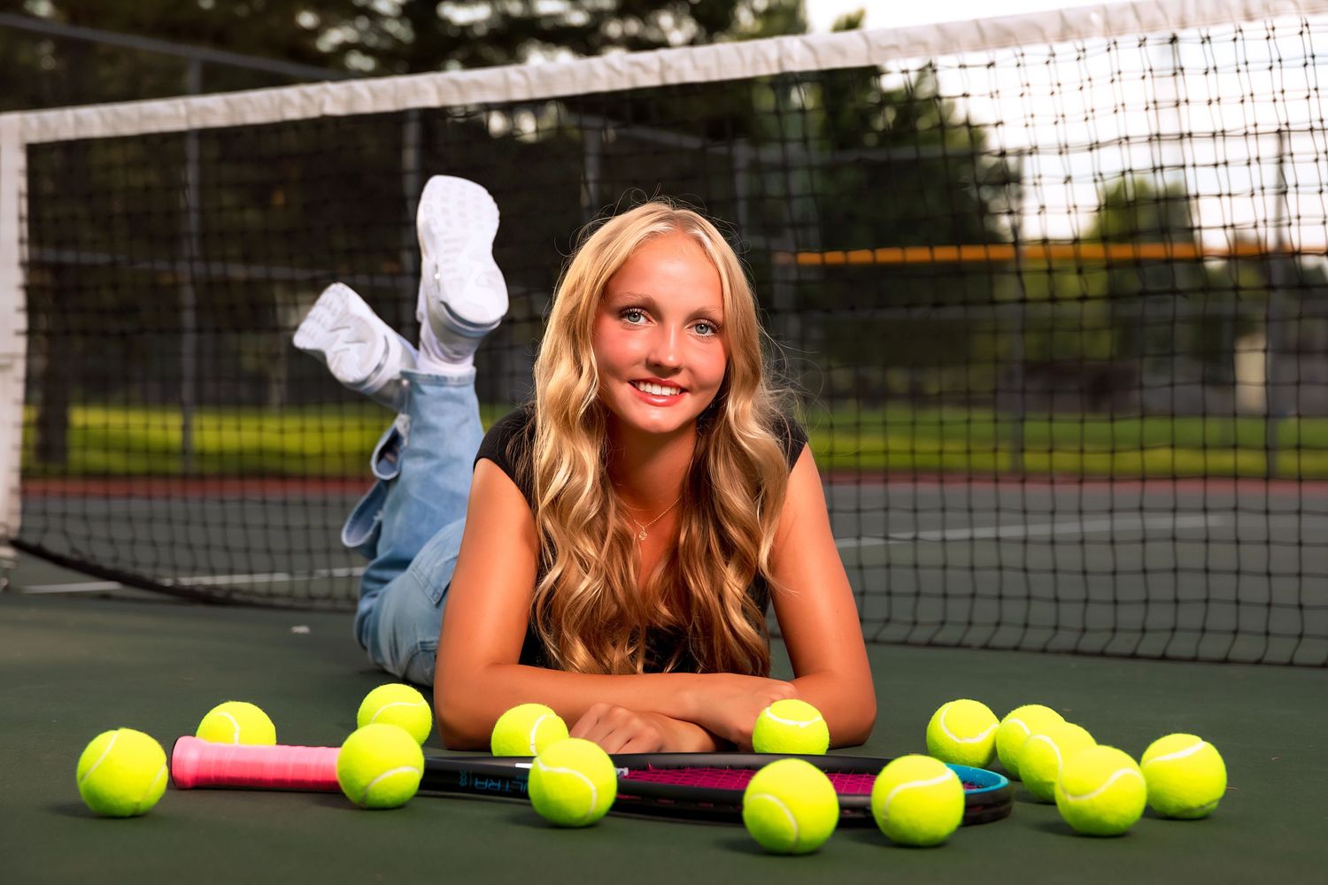 Athletic photo shoot on tennis court with tennis balls and net.
