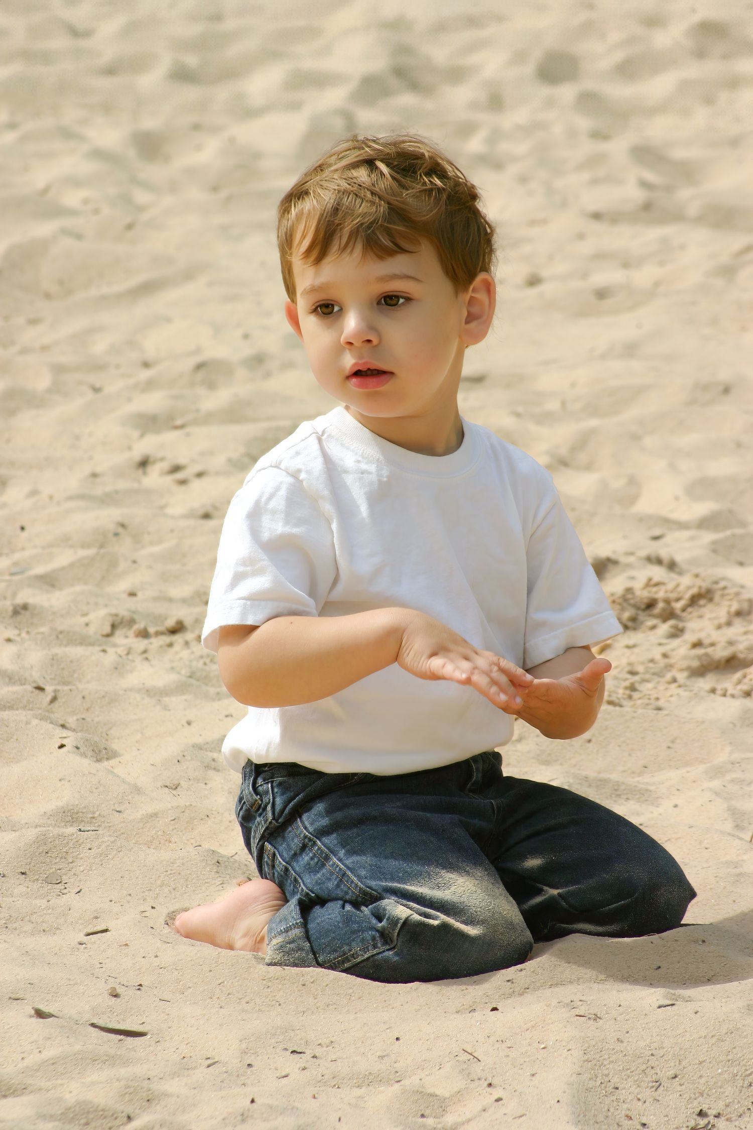 Candid portrait of expressive cute young boy kneeling in the sand at Stone Mountain Park—warm, happy, and tender. Photography by Rachel.