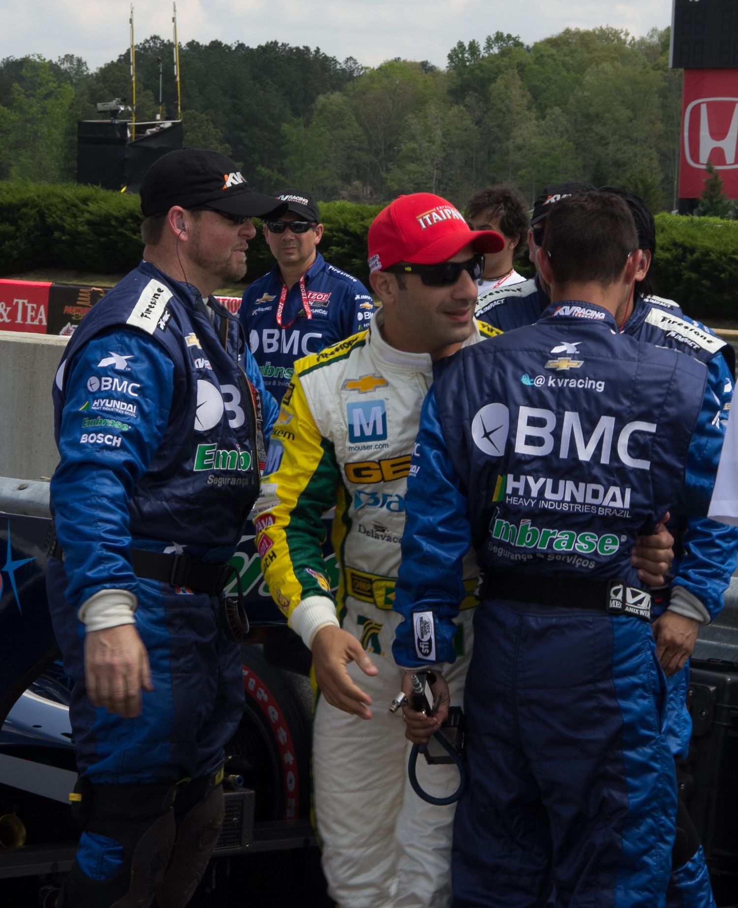 Candid portrait of Helio with his racing team Birmingham, AL—Formula One energy, racing vibe, paparazzi-style photo.