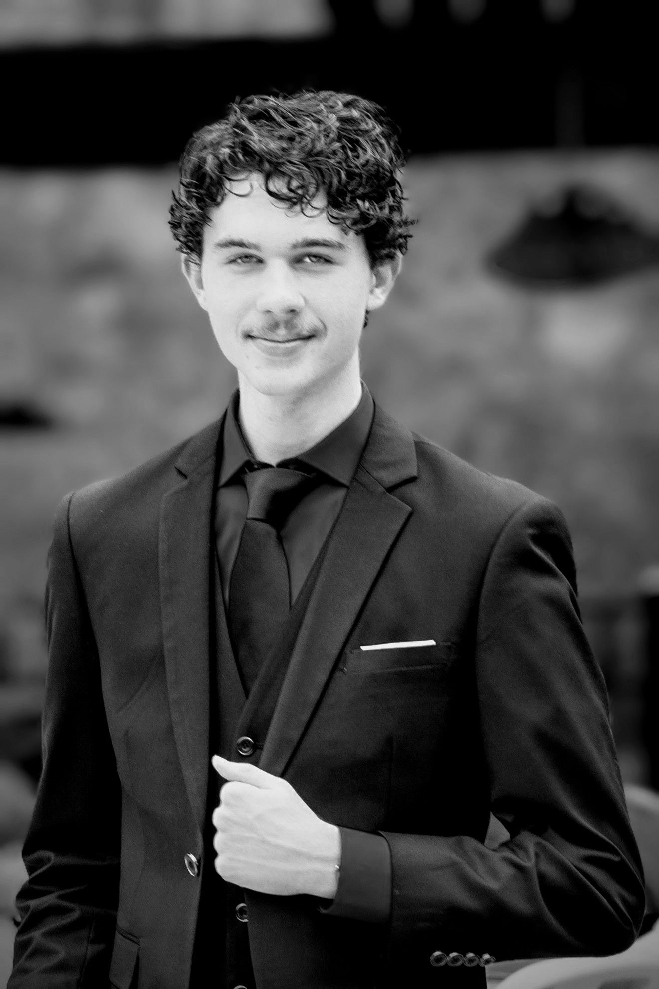 Black and white portrait of a high school senior in a suit at a prom dinner event—natural light photo taken in Pace, Florida.
