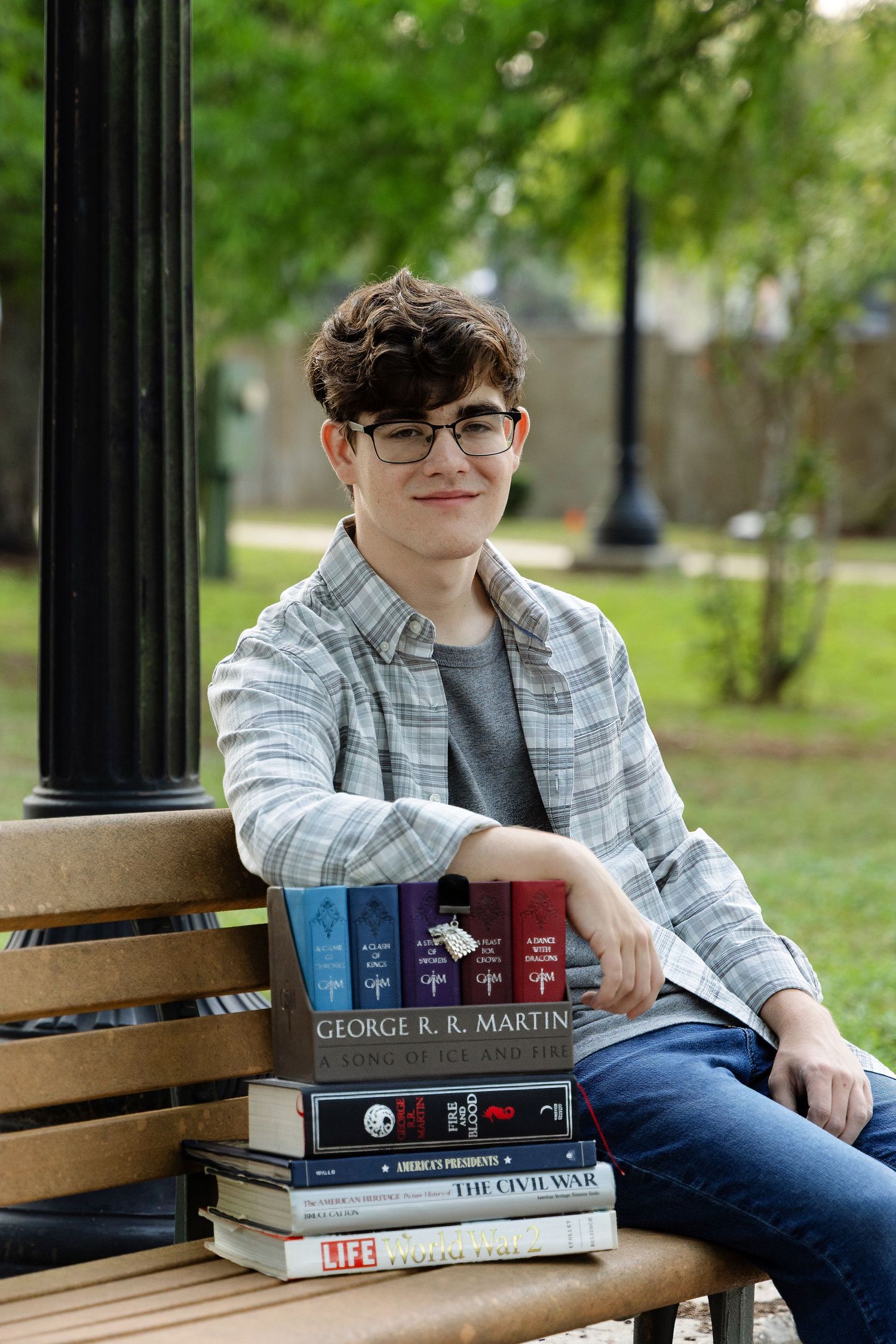 Class of 2025 senior portrait, posed with favorite history books on park bench at Milton Riverwalk, Santa Rosa County, FL.