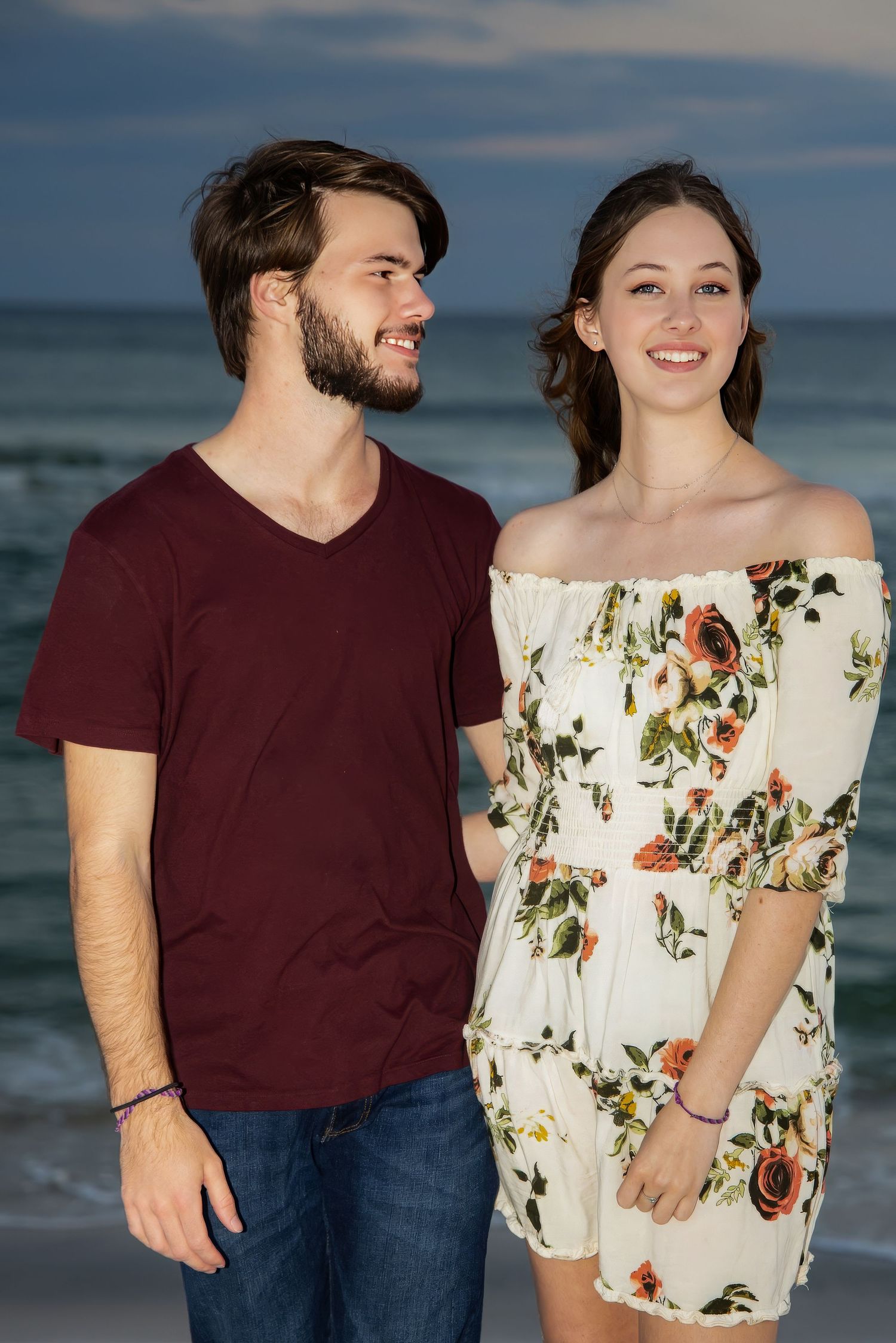 The Look of Love: beach couple portrait, Pensacola FL—he gazes at her, she smiles at camera; warm light, cropped thigh-up, full of heart.