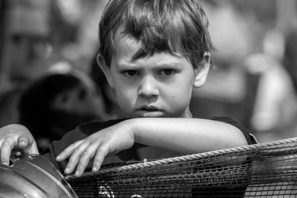 B&W candid child portrait—moody 6-year-old t-ball player in Santa Rosa County, FL, expressive & bored in the outfield. Photography by Rachel