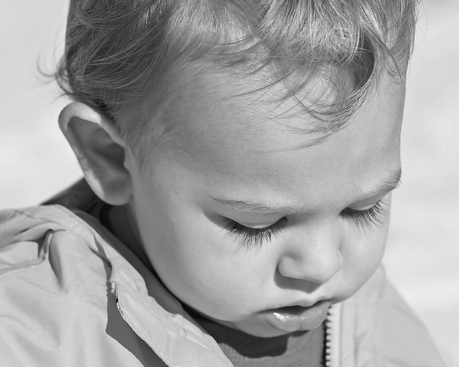 Monochromatic close-up of toddler boy at Perdido Beach—natural light portrait highlighting lashes and emotion. Photography by Rachel.