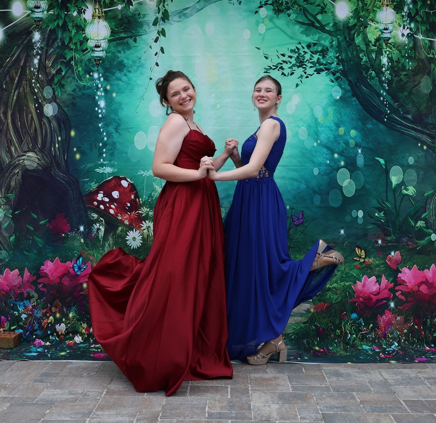 Candid prom portrait of 2 girls in bold formal dresses, holding hands and striking playful pose. Prom dinner, Pace FL