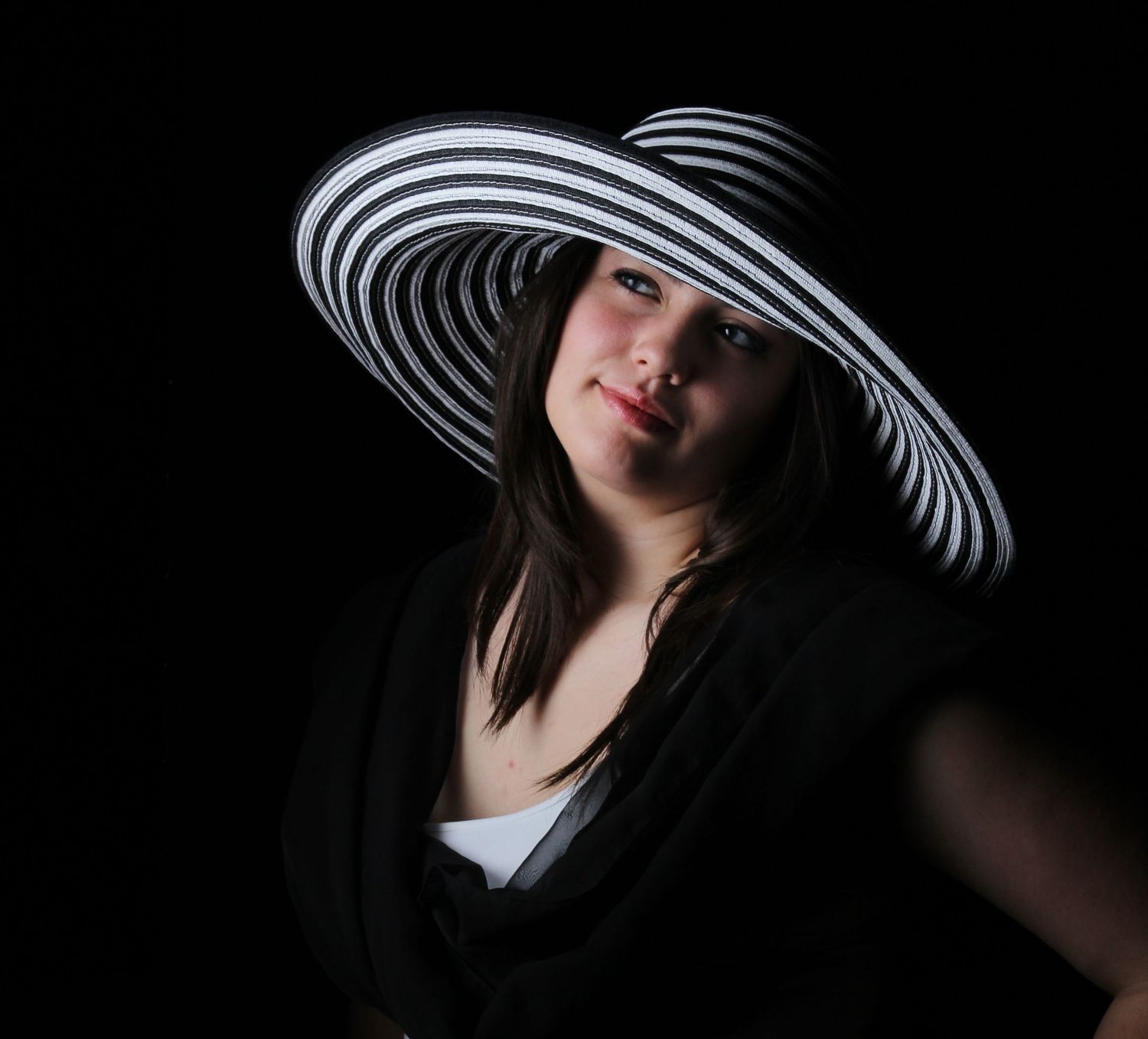 Studio portrait of model Ariel in Pensacola, FL—dramatic full-color image with striking black & white wide-brimmed hat. Photography by Rache