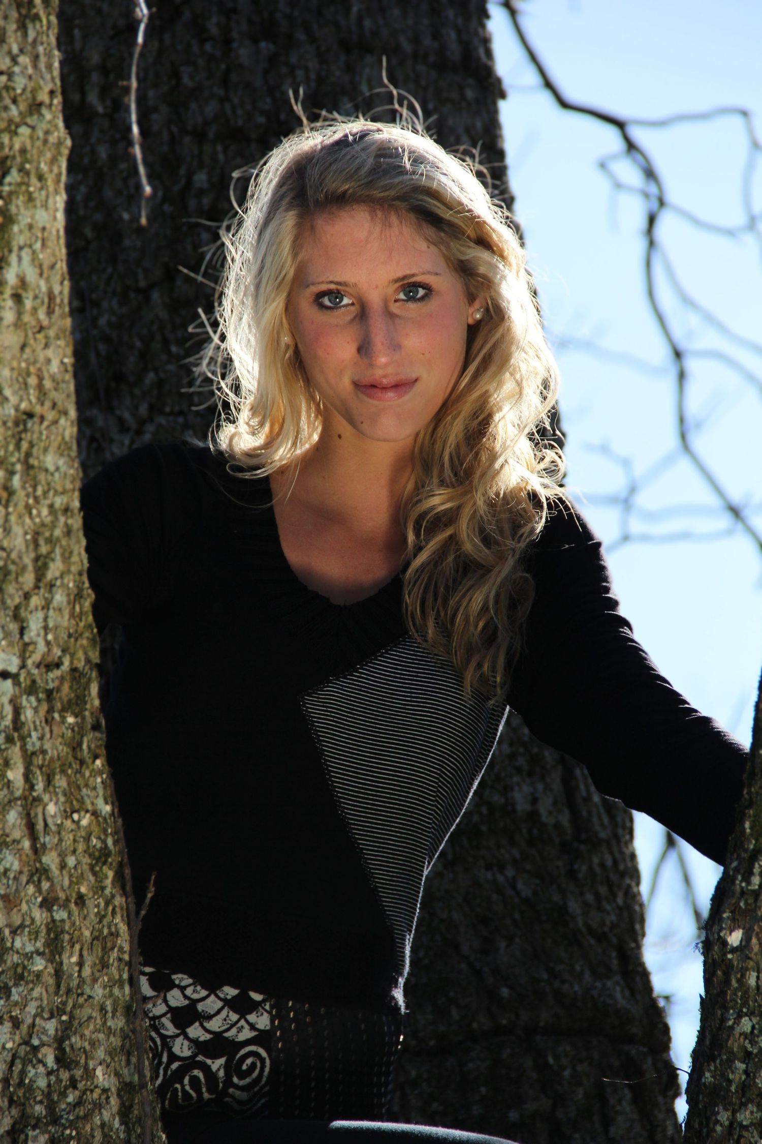 Natural light portrait, female model backlit by sun while looking down from a large oak tree. Pensacola, FL. Photography by Rachel.