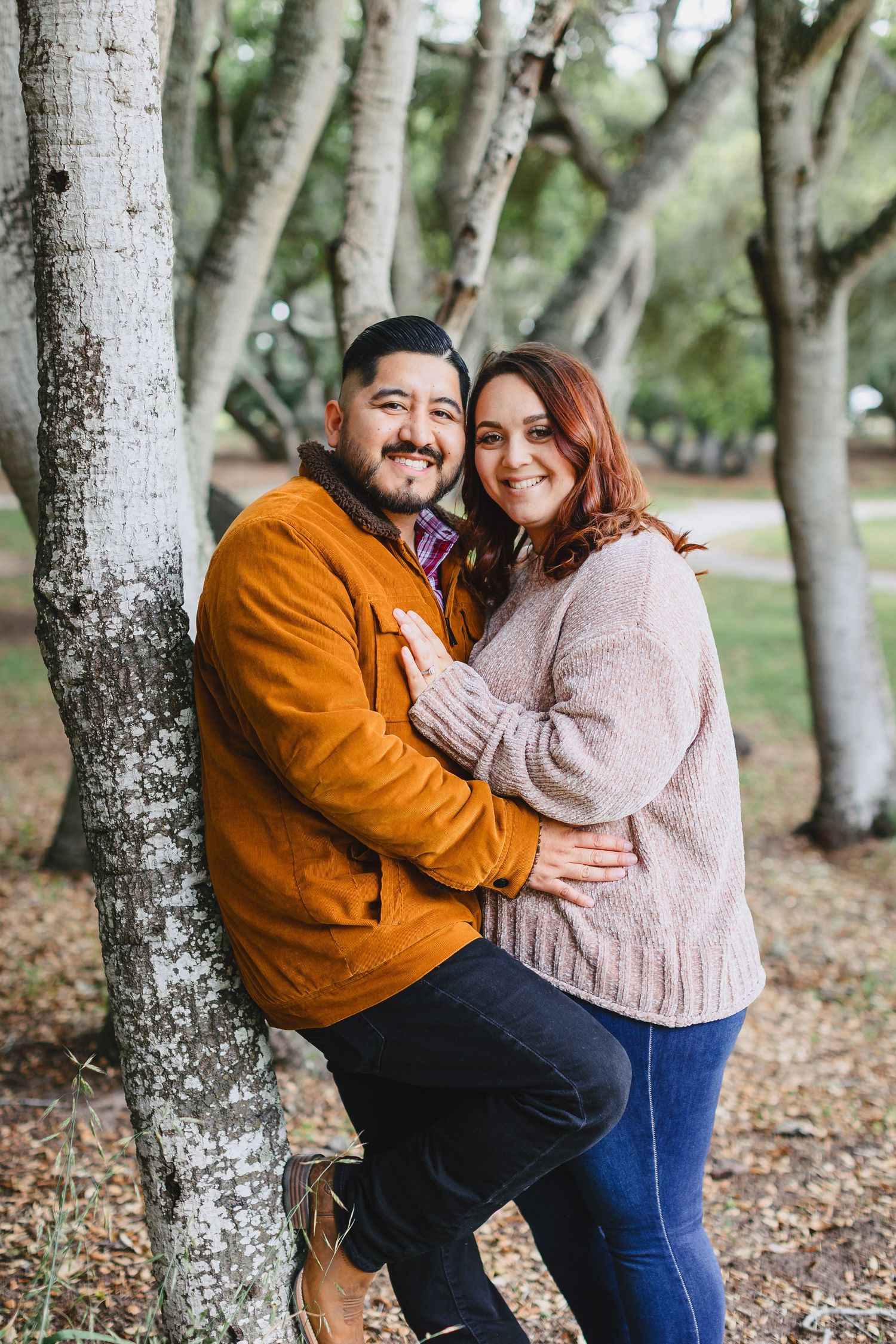 Couple in sweaters embracing among birch trees in autumn.