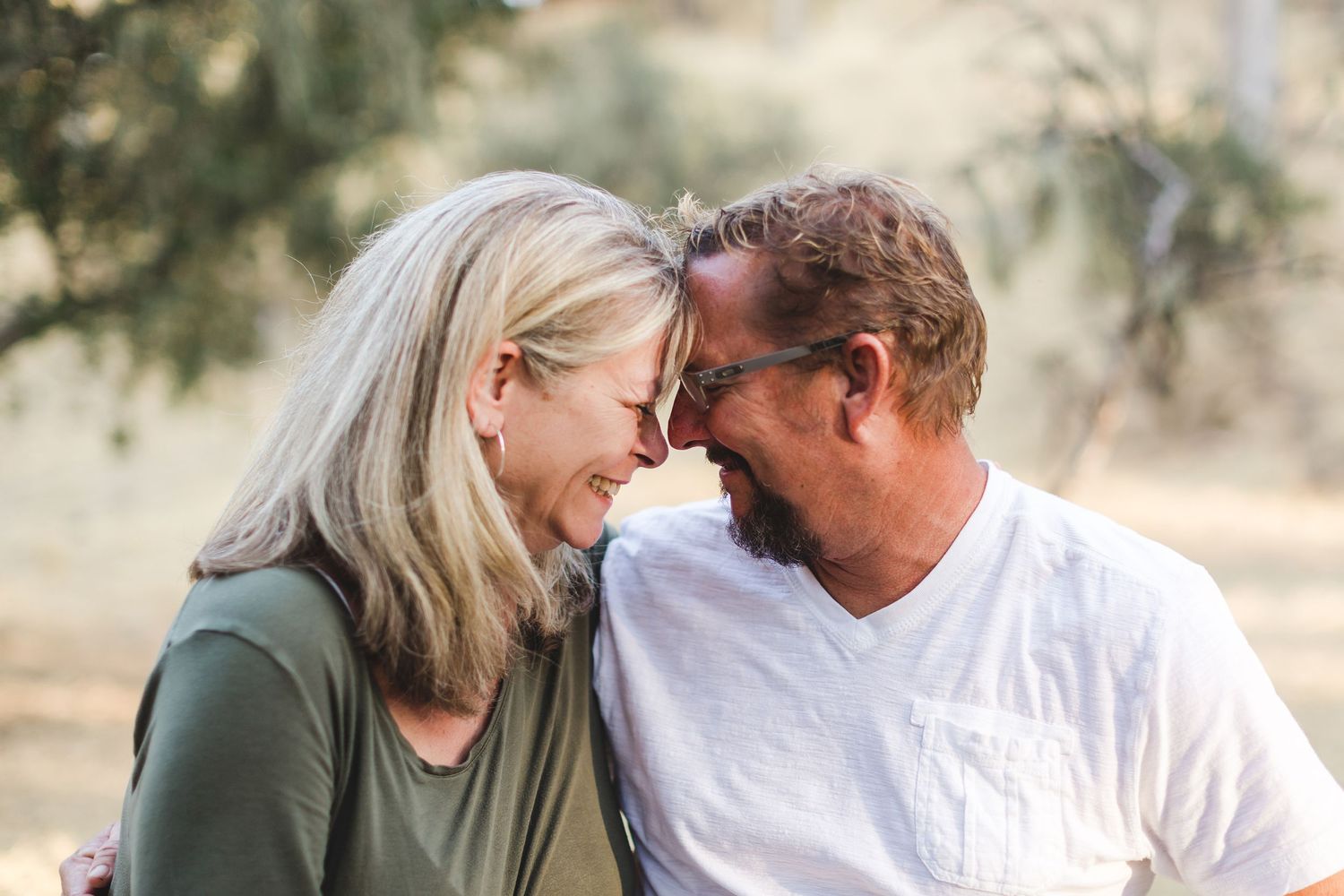 Mature couple sharing tender moment outdoors with soft natural lighting.