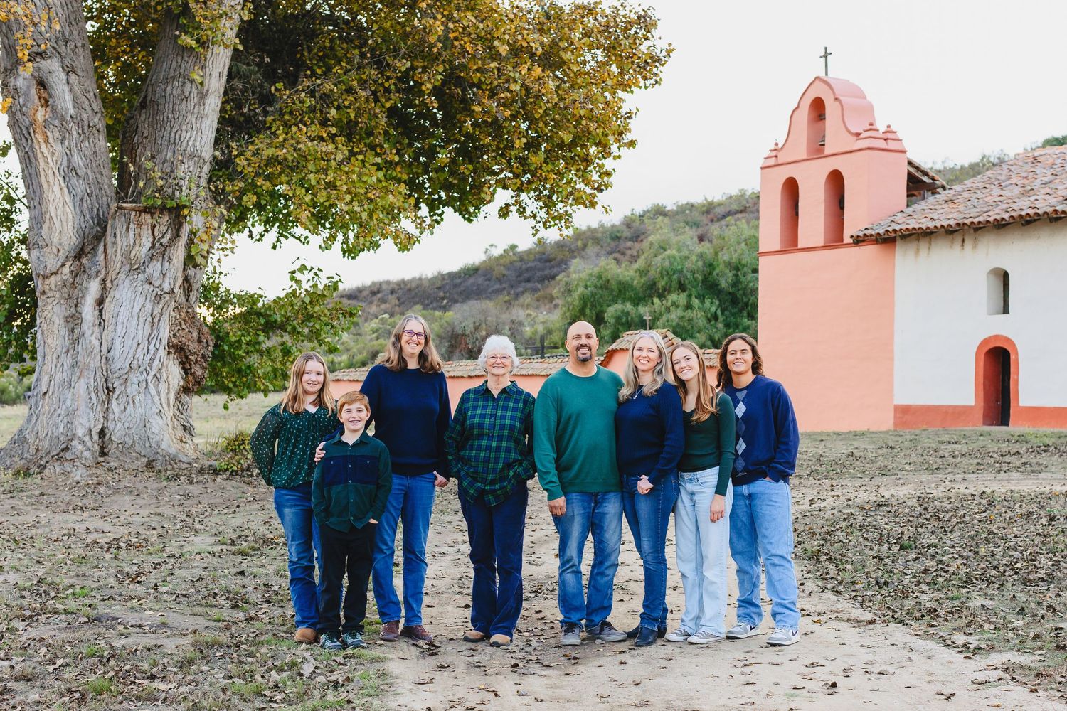 A group portrait of people standing together in front of a pink Spanish-style church building.