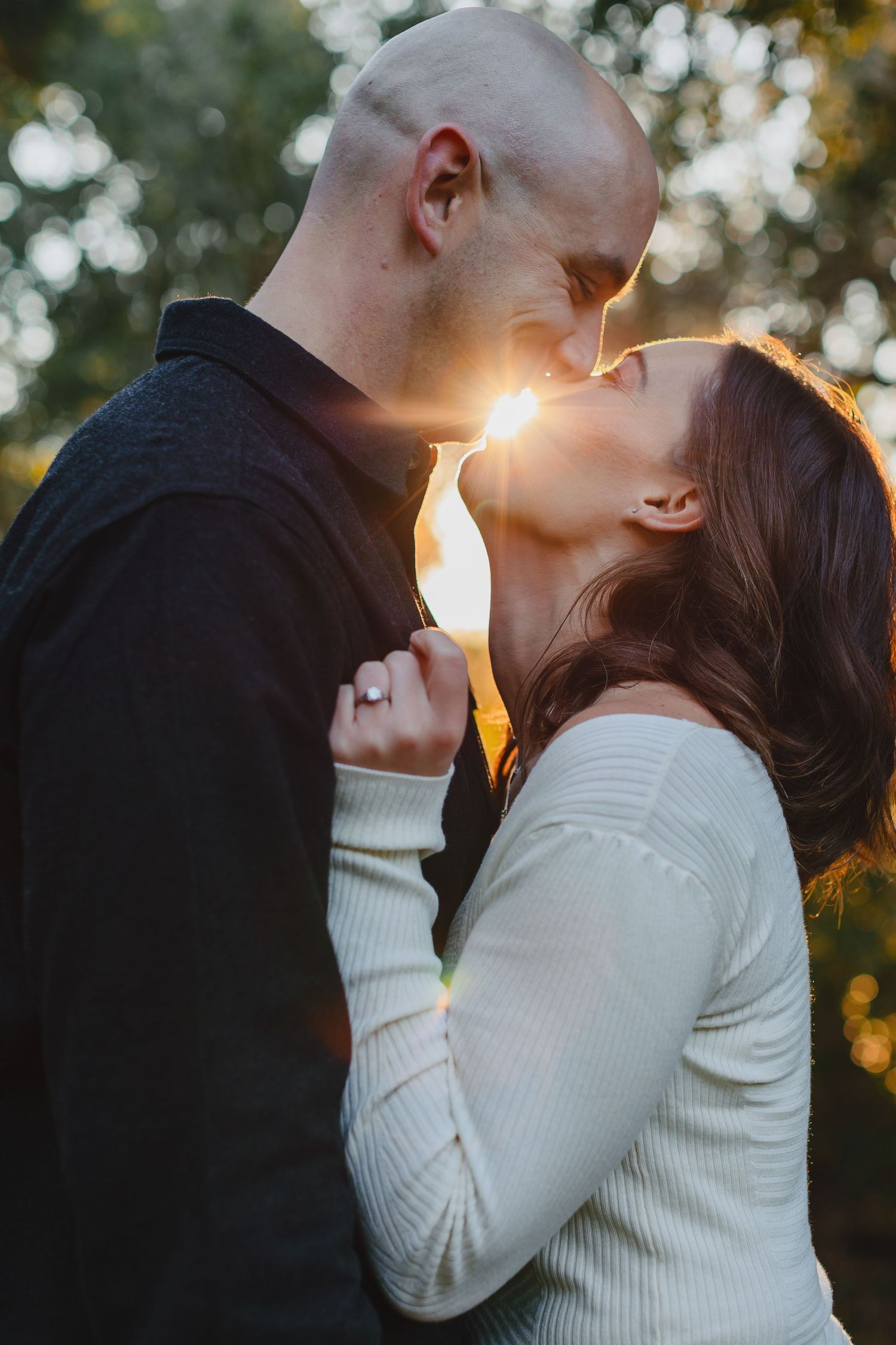 Intimate moment between couple backlit by golden sunset.