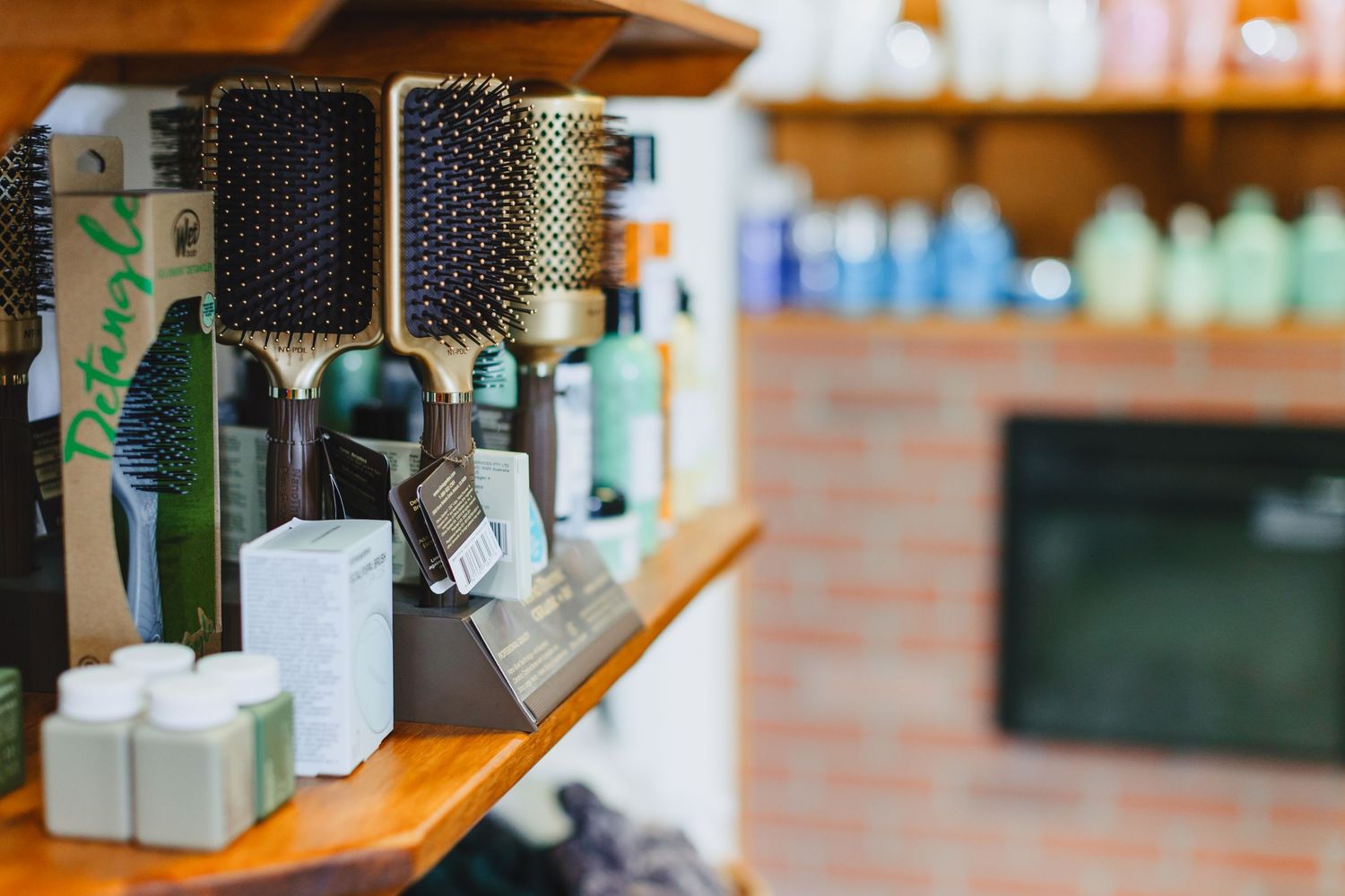 Professional hairbrushes and styling products arranged on wooden salon shelves.