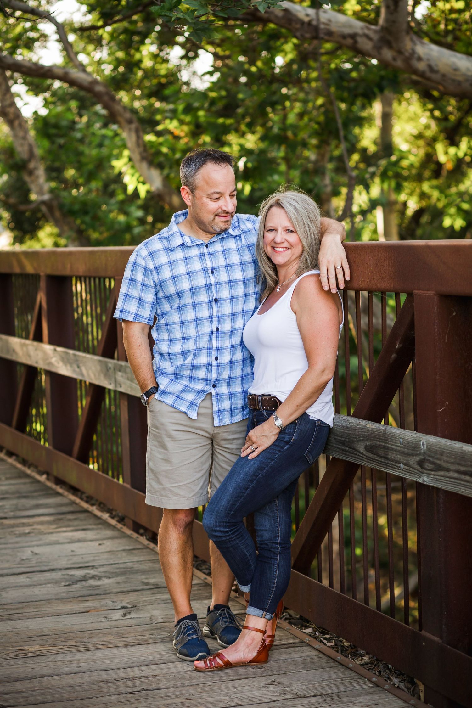 Couple sharing a romantic moment on a wooden bridge surrounded by lush greenery.