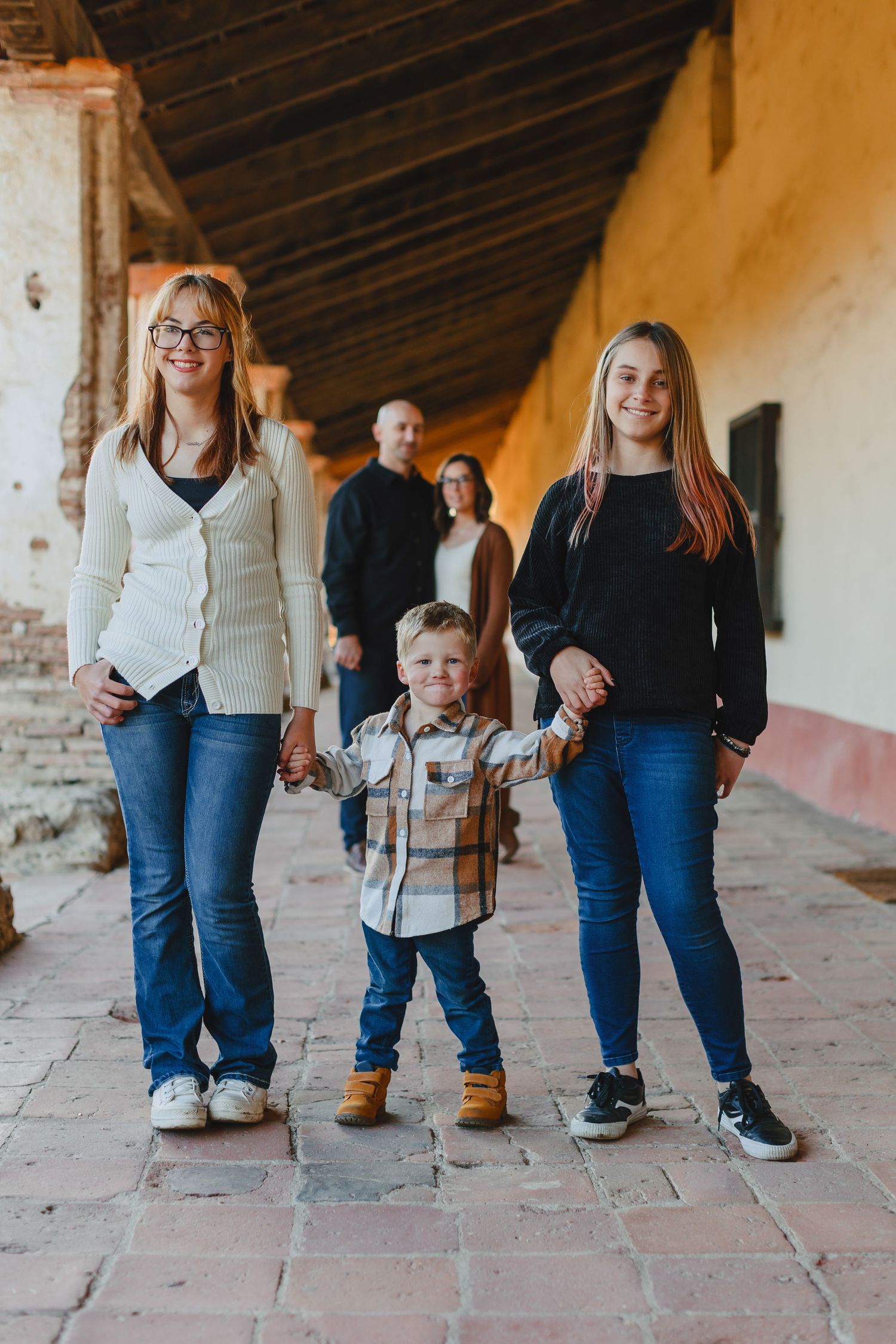 A casual family portrait taken under a mission-style covered walkway.