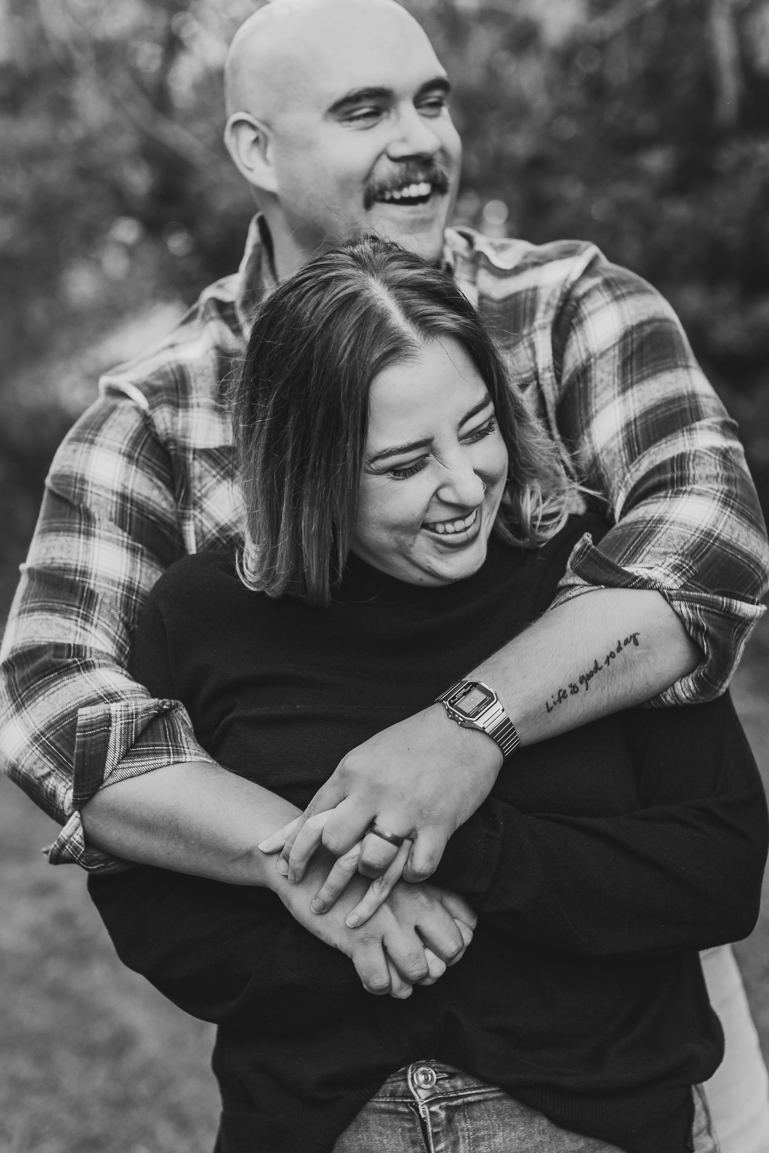 A candid black and white photo of a couple embracing, showing tattoo detail.