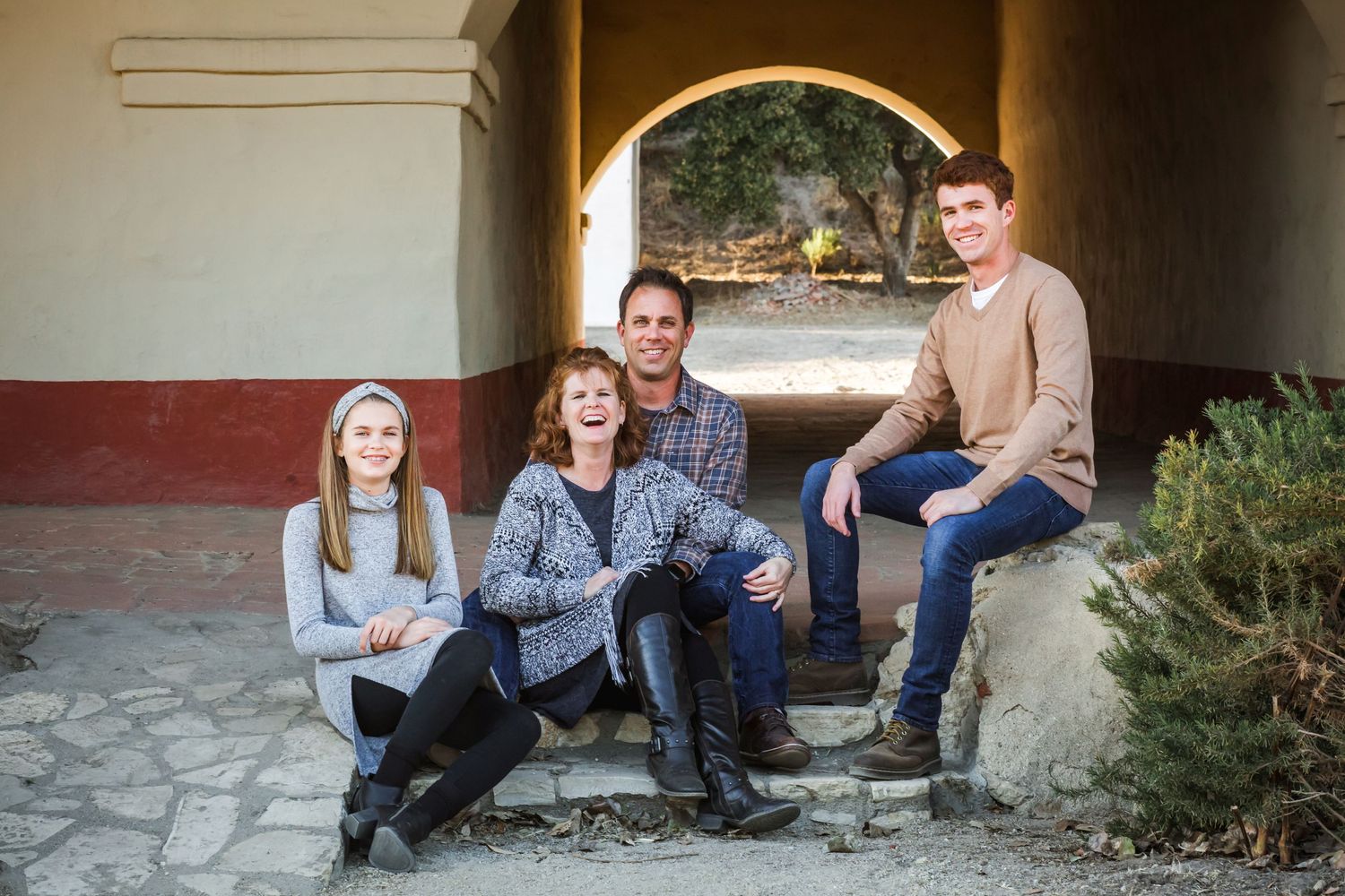 A group sits together under a stone archway during an outdoor portrait session.