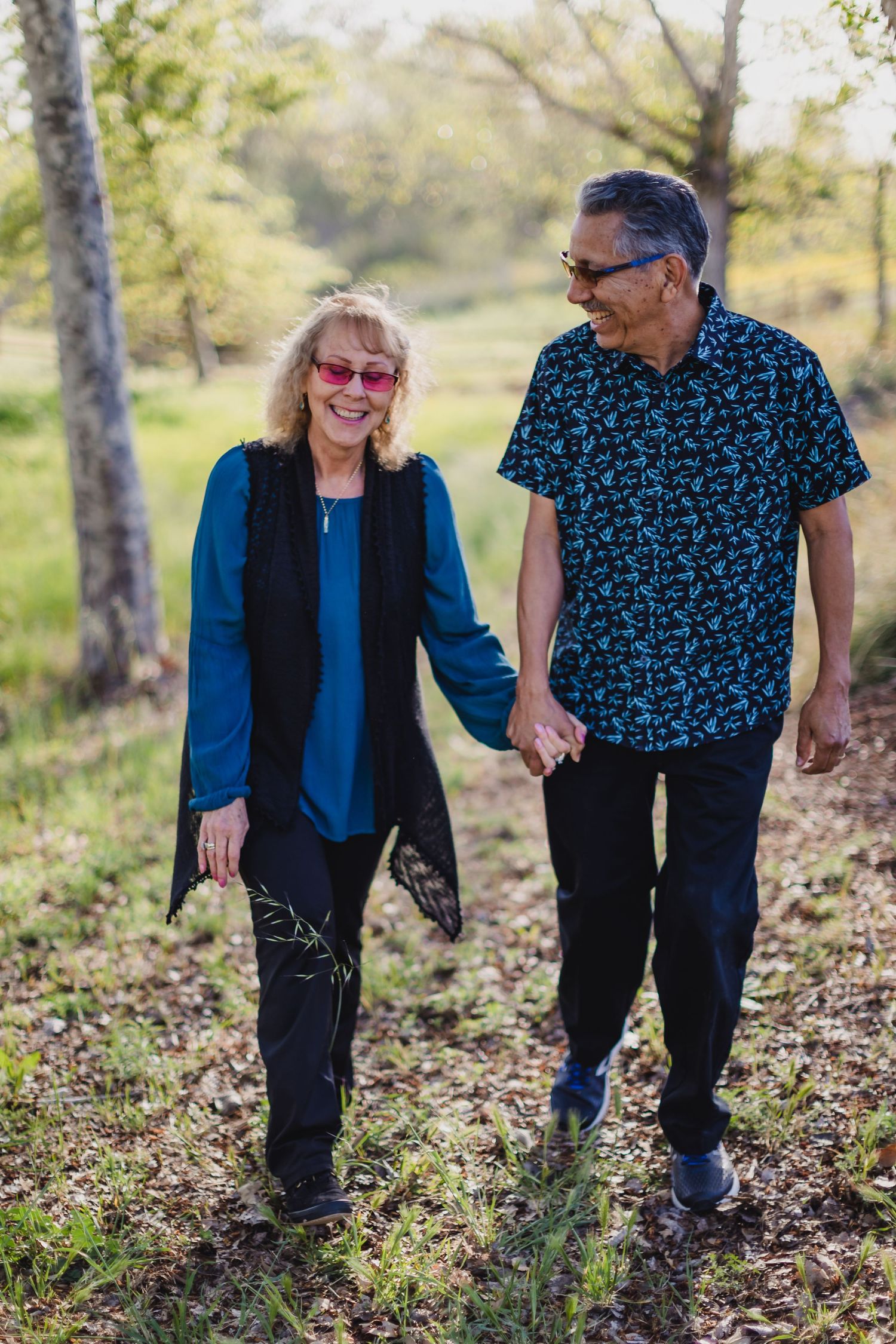 Mature couple walking hand in hand through a park on a sunny day.