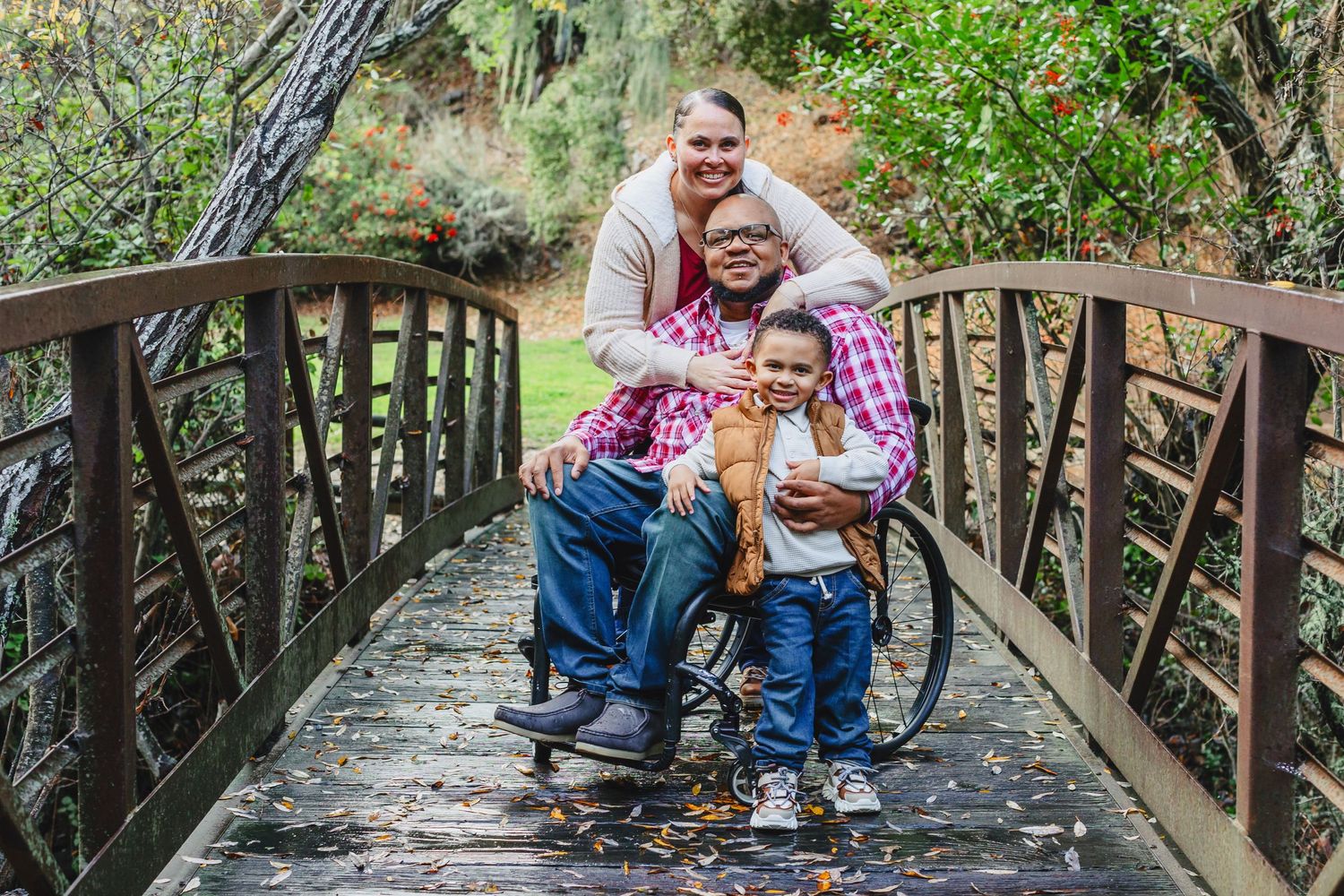 Family sharing a tender moment together on a wooden bridge in nature.