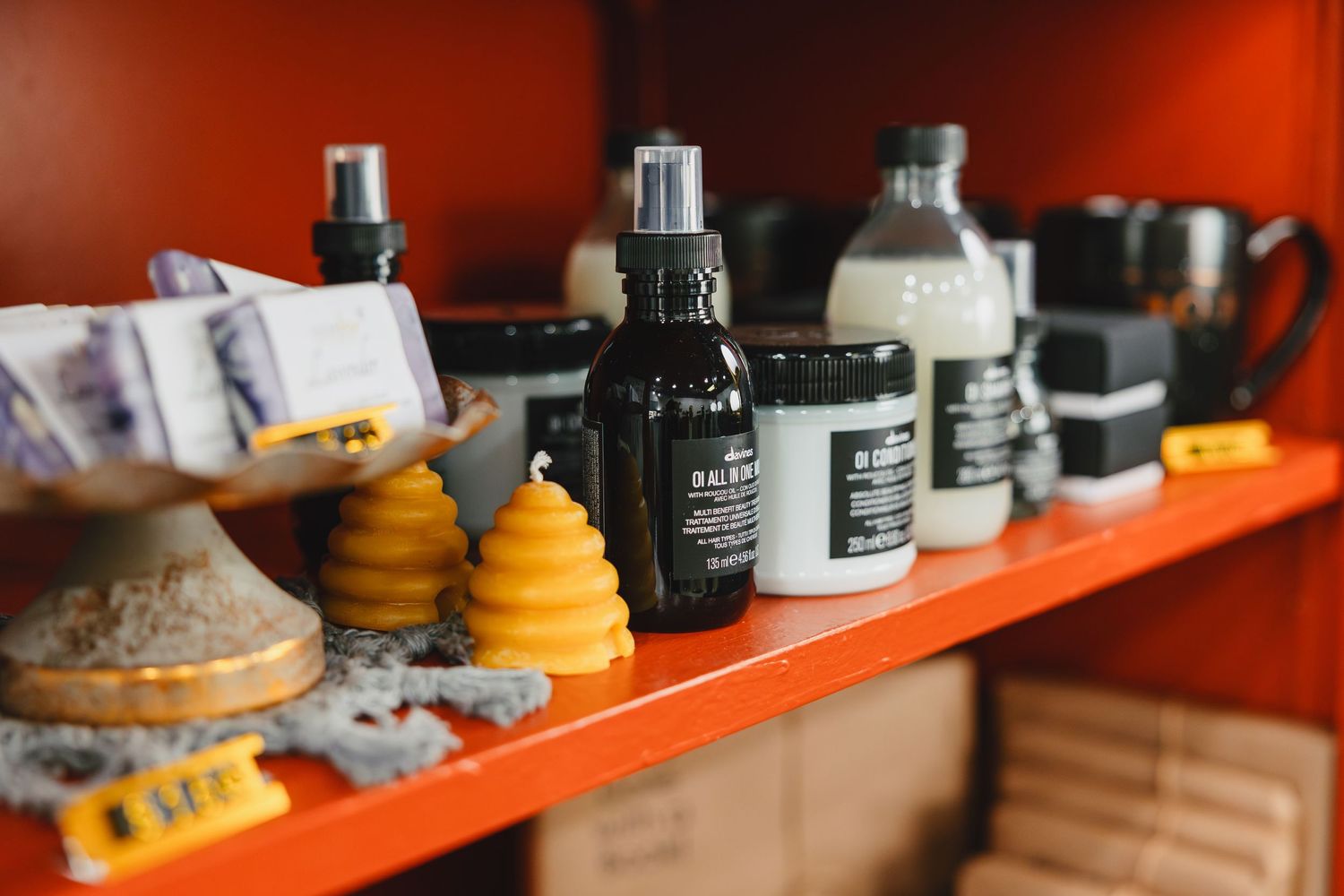 Various bottles and beehive-shaped products arranged on an orange shelf in a store display.