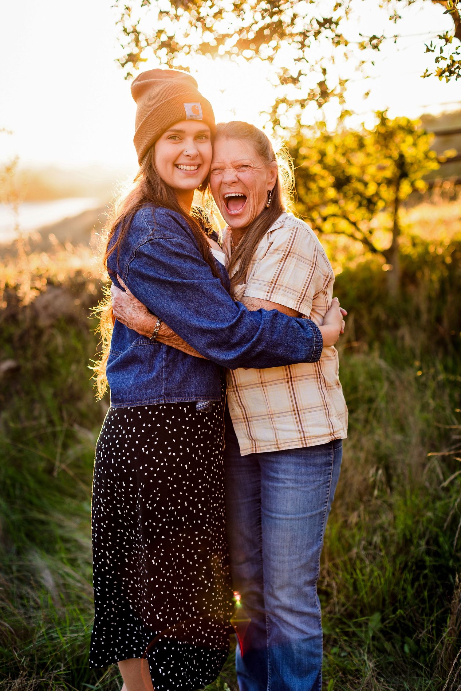 Two people sharing a warm embrace while laughing during golden hour.