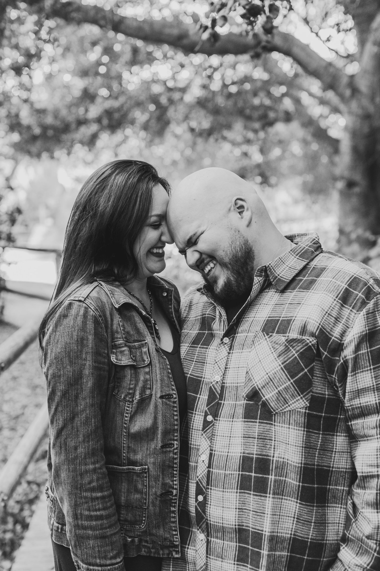 An intimate black and white portrait of a couple sharing a tender moment outdoors.