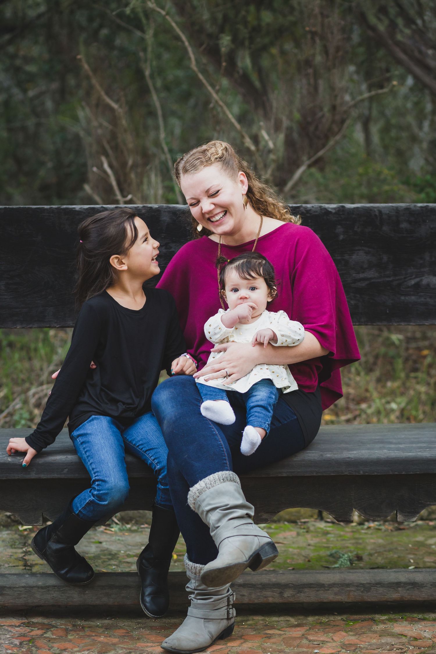 A sweet candid moment shared on a wooden bench in a park setting.
