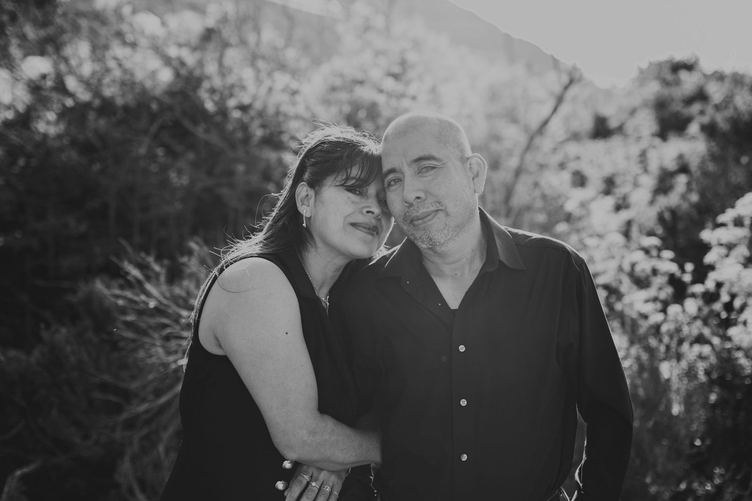 Black and white portrait of couple sharing tender moment outdoors.