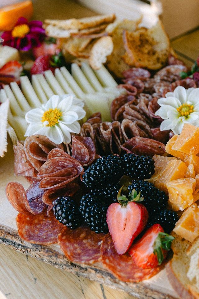 Gourmet charcuterie board with fresh berries, cheese, and edible flowers.