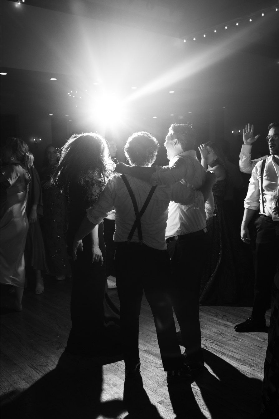 Silhouettes of wedding guests dancing under dramatic lighting at an evening reception.
