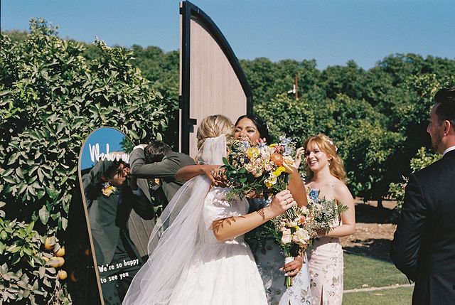 Wedding celebration with decorated arch and floral arrangements in garden setting.