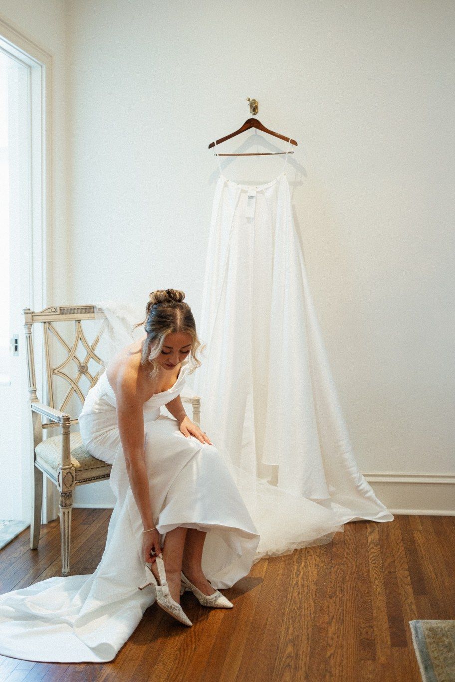 Sequence showing someone getting ready for a wedding, putting on white shoes and arranging a dress in a bright room.