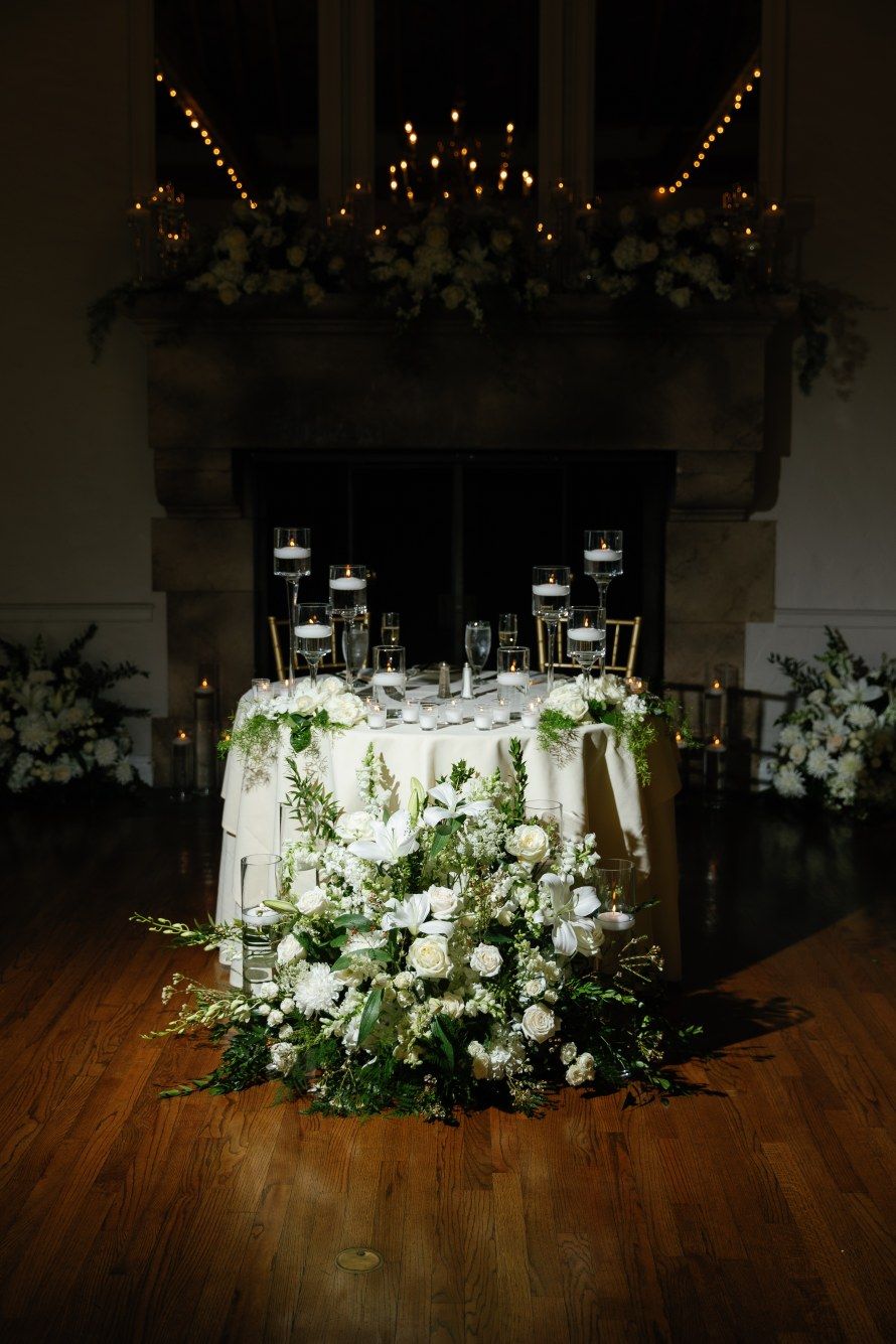 White floral arrangements and lanterns create an elegant wedding reception centerpiece display.