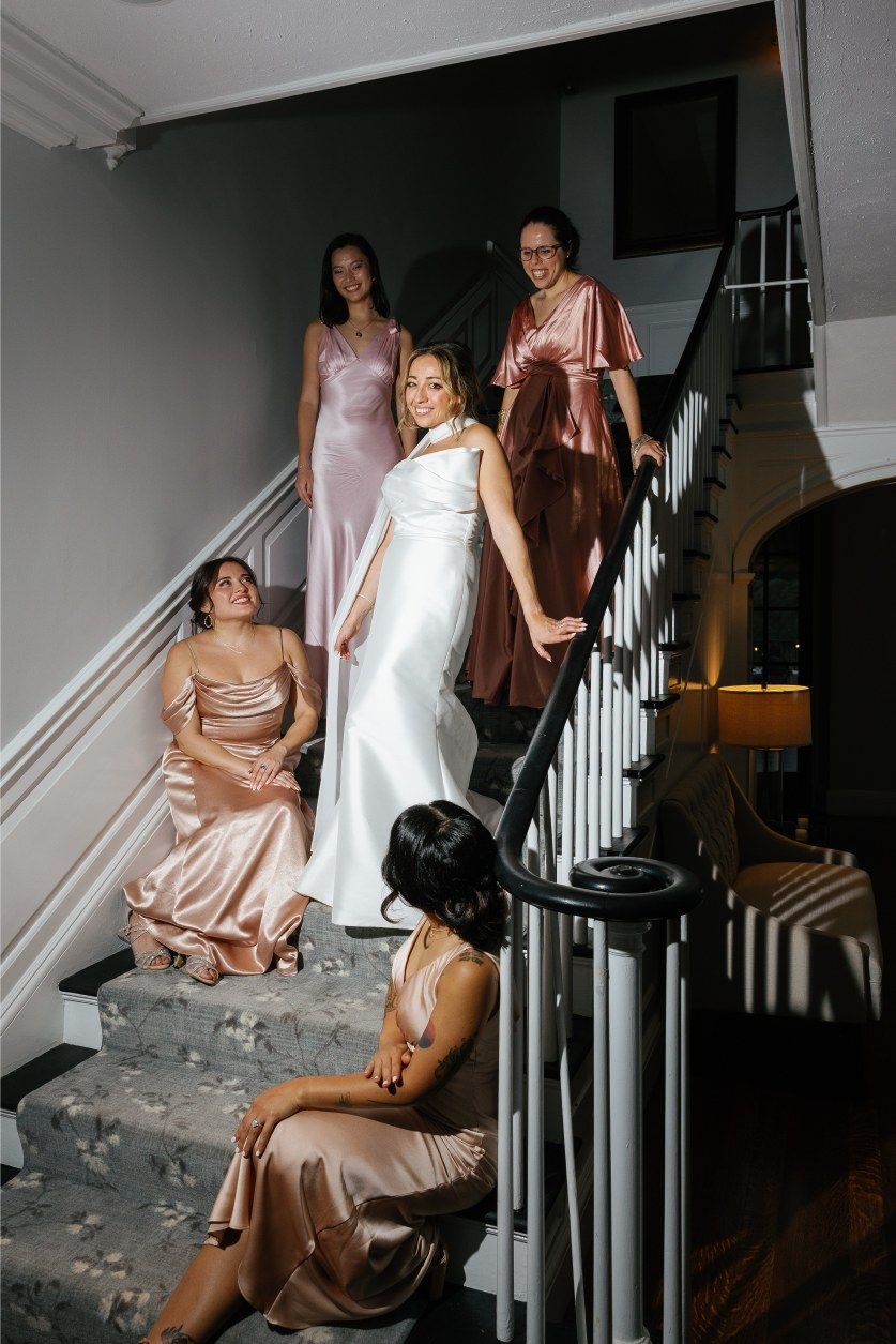 Wedding party gathered on an elegant white staircase in formal attire.