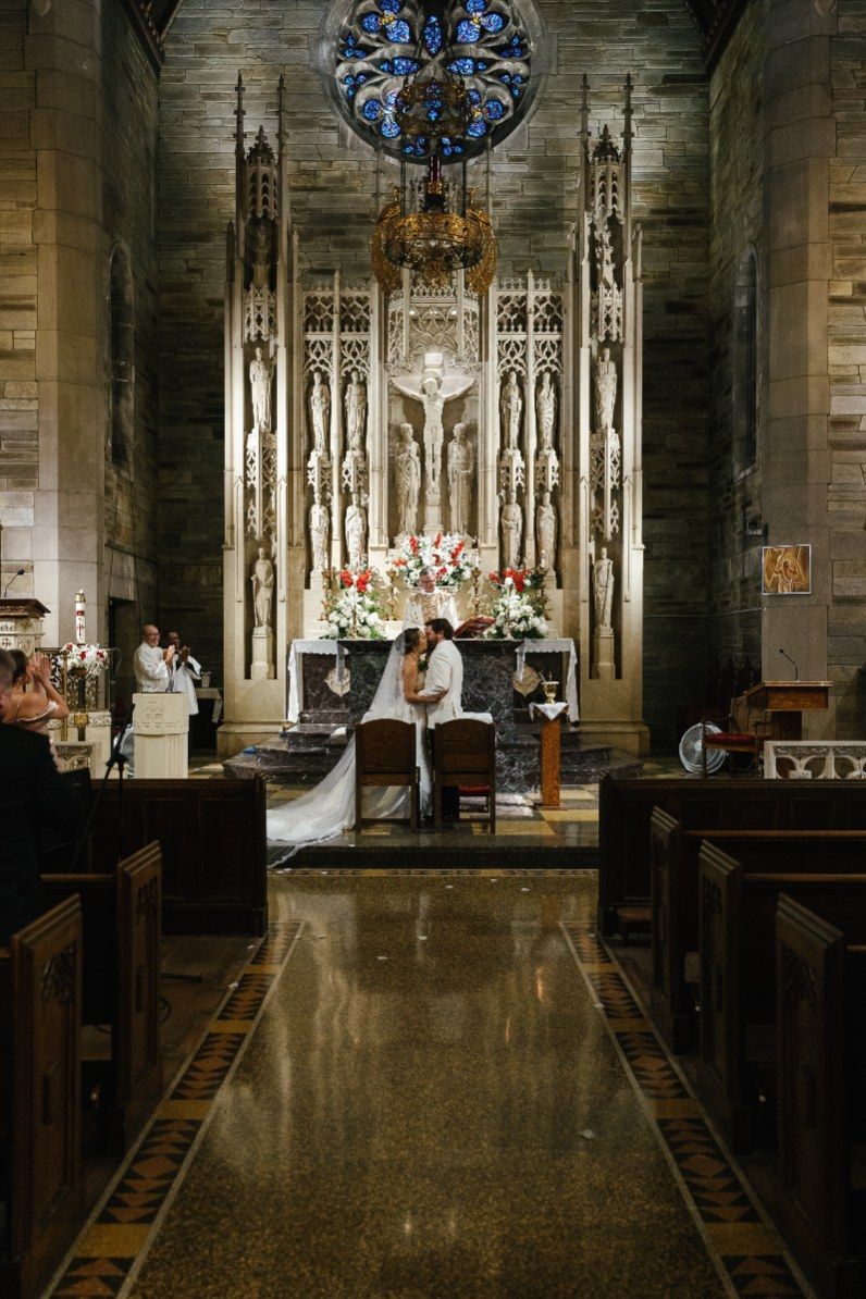Gothic church interior with stained glass windows and ornate altar during a wedding ceremony.