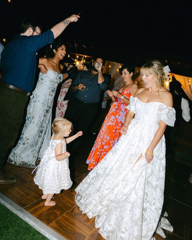 Wedding party dancing together on a wooden dance floor during an evening reception celebration.