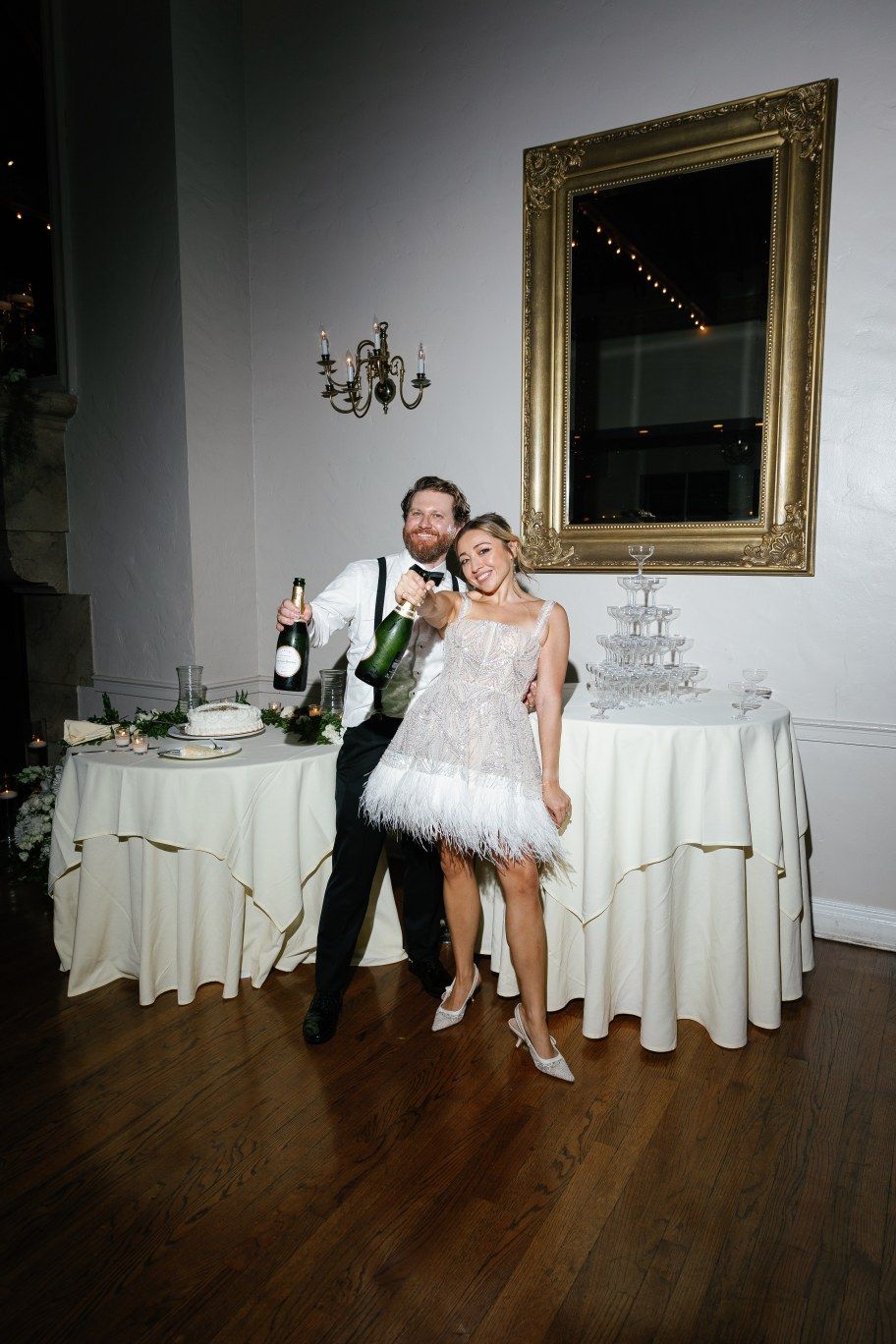 A celebratory moment at a wedding reception with champagne by candlelit tables with elegant decor and a gold-framed mirror.