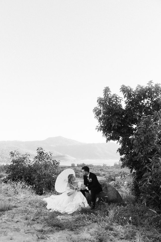 Black and white portrait of couple sharing intimate moment on hillside.