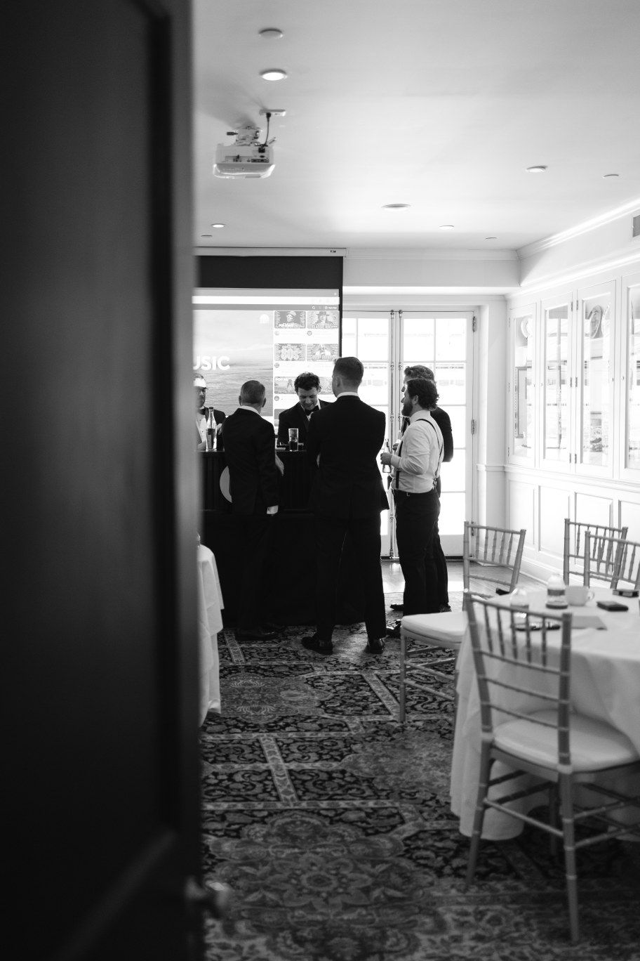 A sequence of black and white photos showing a hallway with white chairs and patterned carpet at what appears to be an event venue.