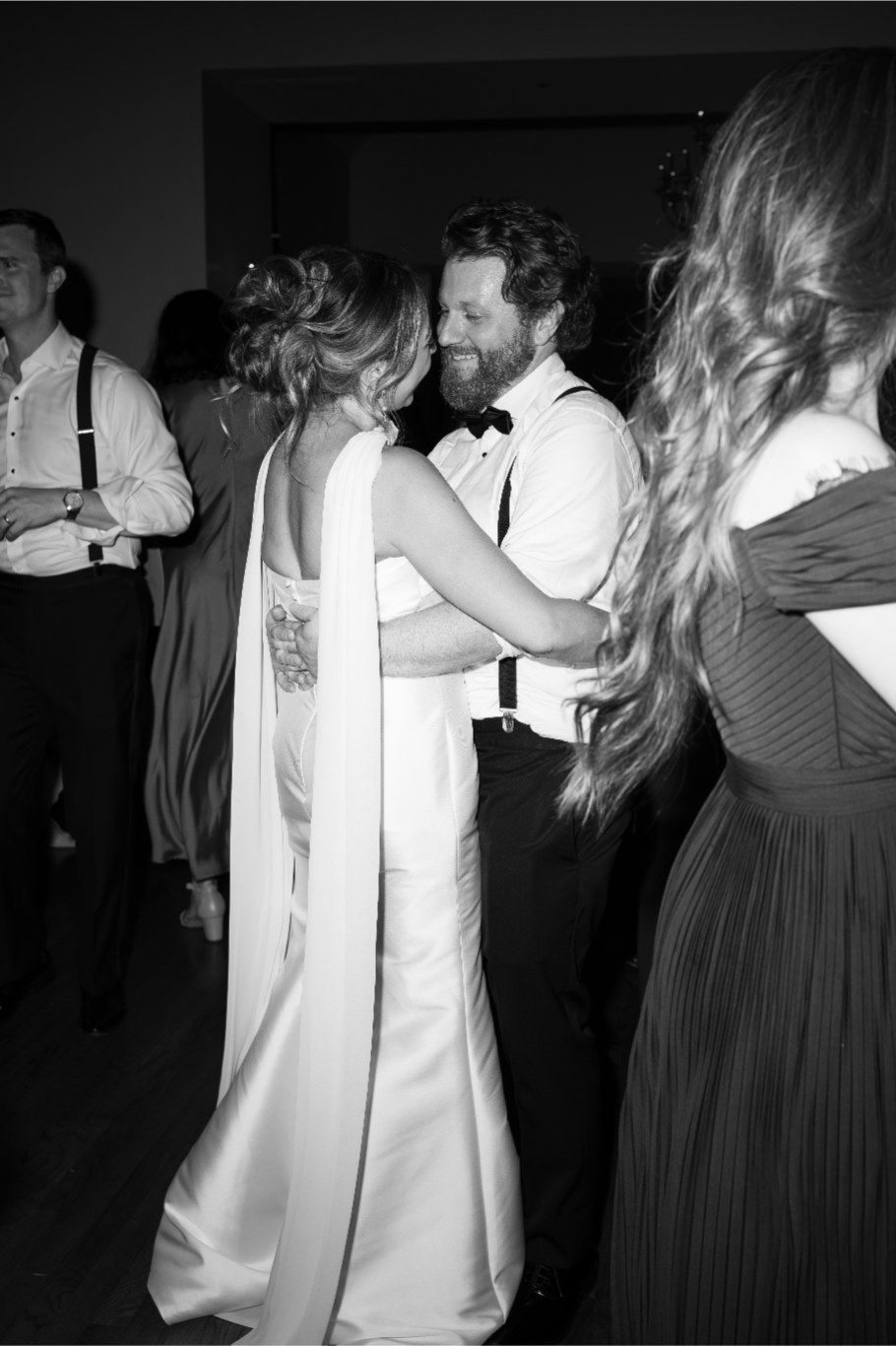 Couples dancing together during a dimly lit wedding reception celebration.