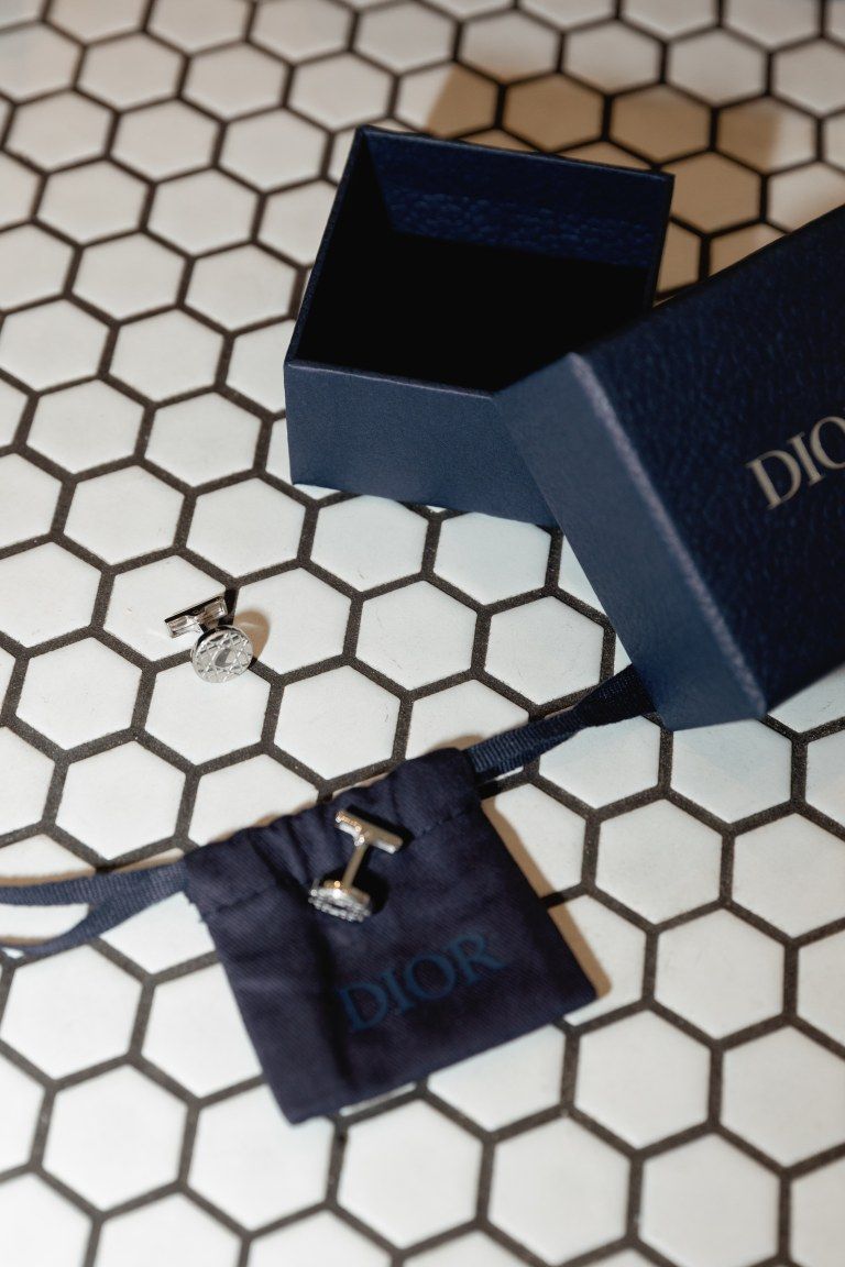 Dior jewelry box and pouch with earrings on white hexagonal tile background.