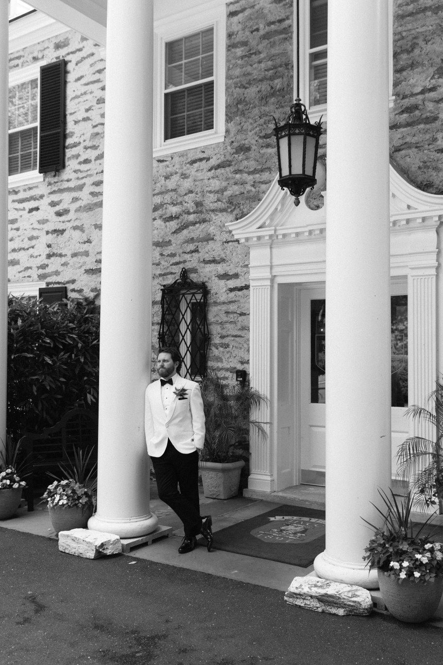 A classic stone building entrance with white columns and lantern fixtures adorning the elegant porch facade.