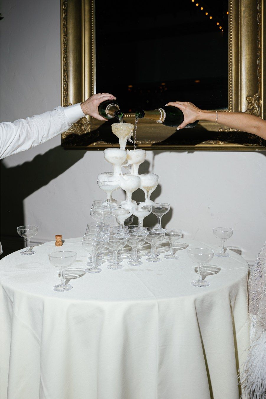 Champagne being poured into a tower of elegant crystal glasses at a wedding reception.