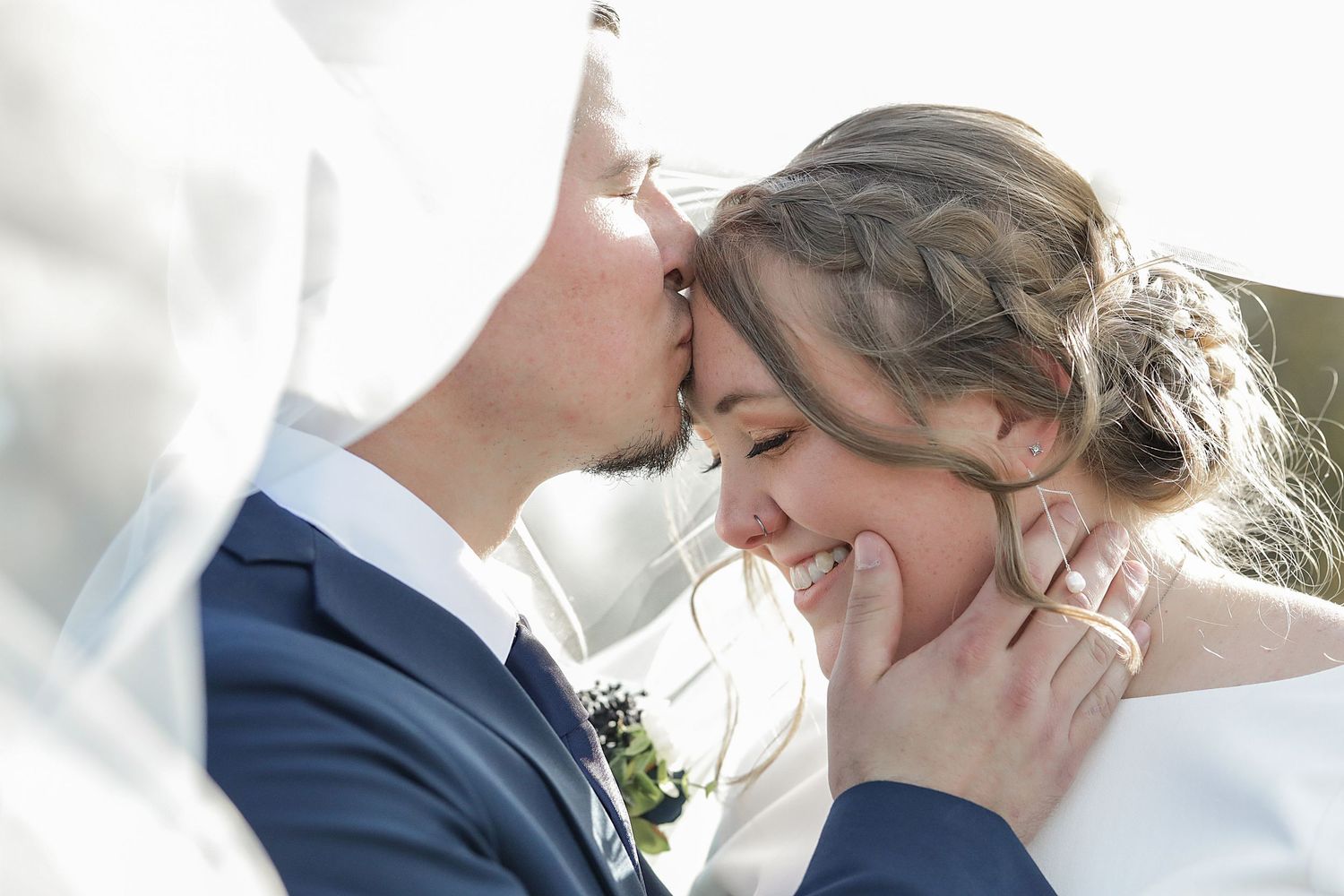 Intimate wedding portrait captured in soft sunlight during outdoor ceremony.
