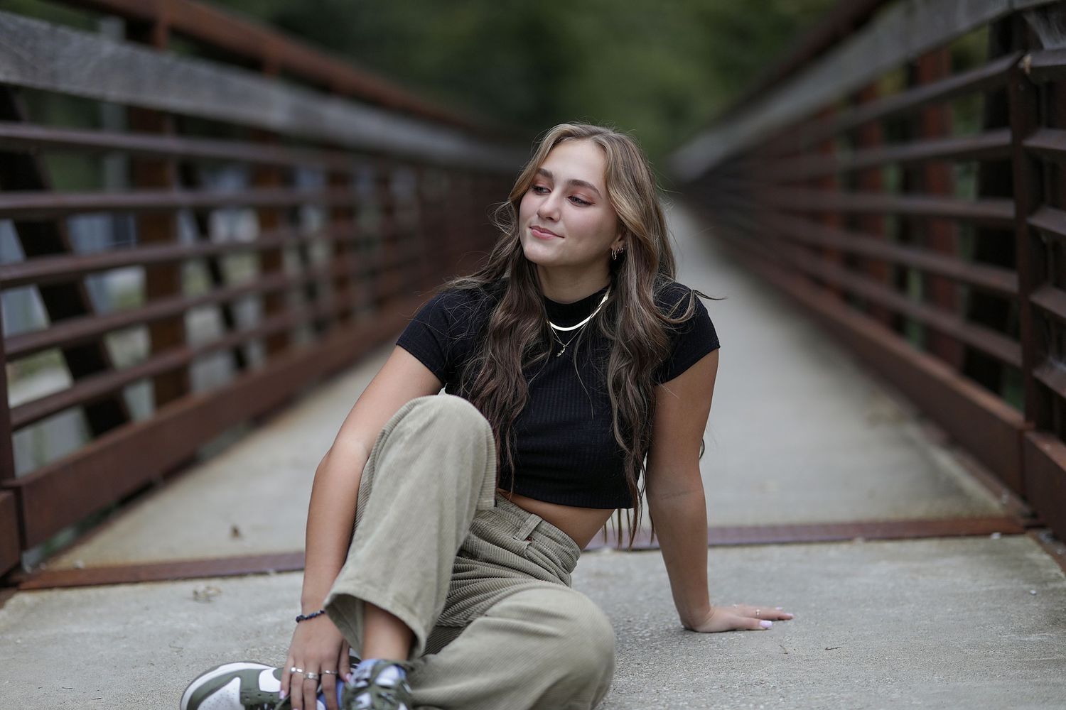 Person in casual attire relaxing on wooden bridge walkway in peaceful outdoor setting.
