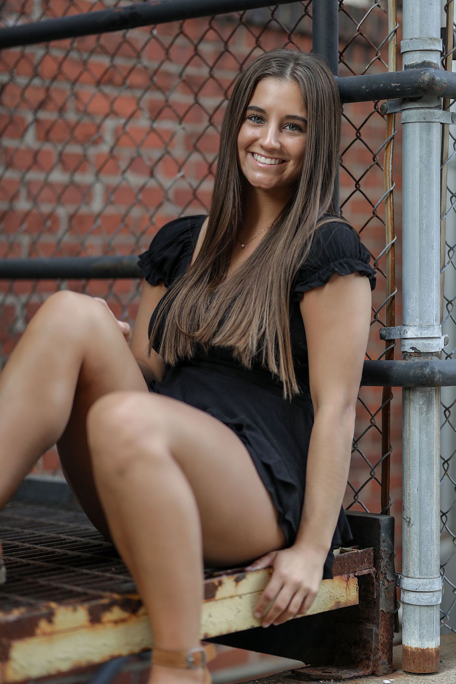 A series of four similar photos showing someone in a black dress sitting on an outdoor bench next to brick walls.
