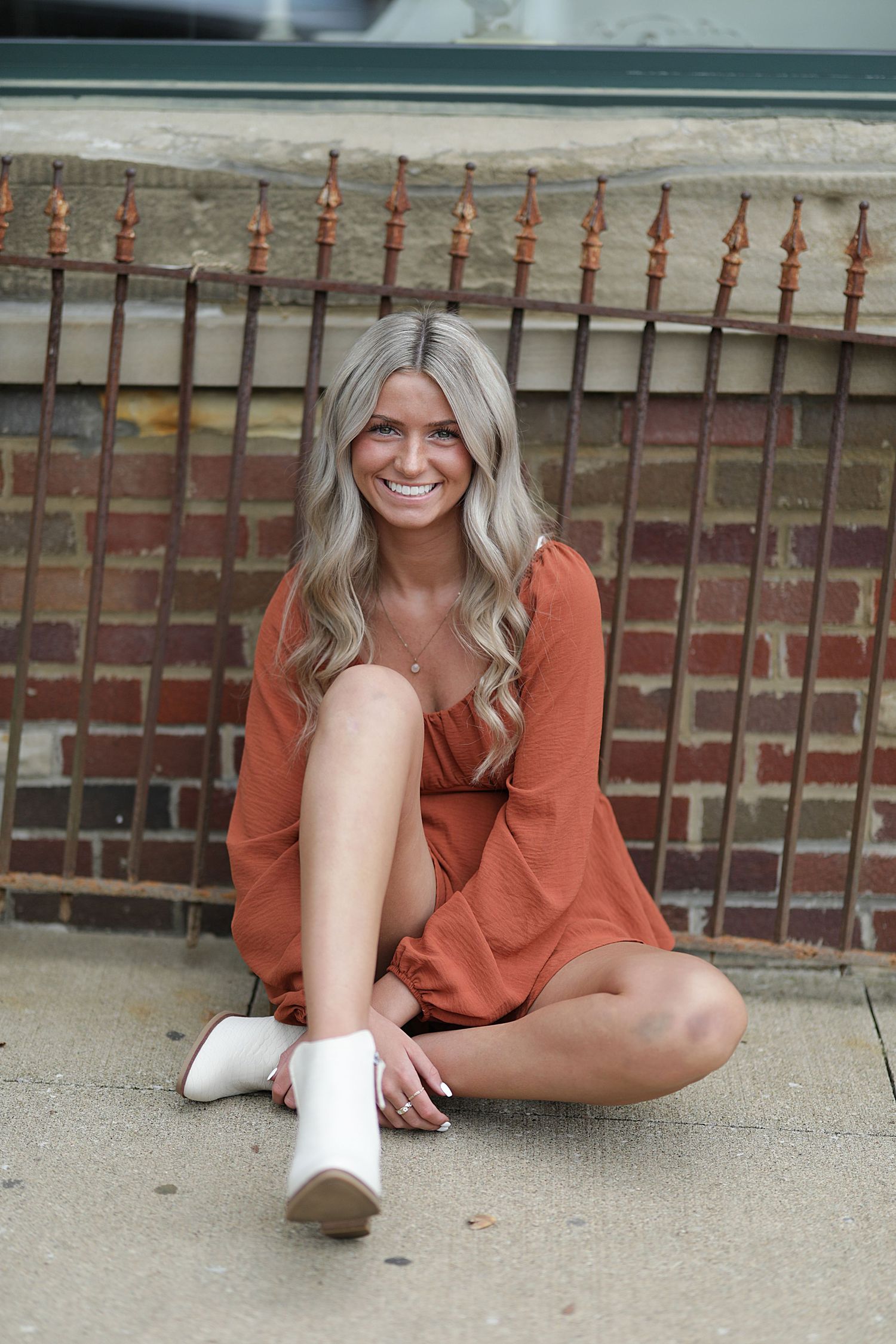 A sequence of fashion lifestyle photos showing a person in a rust-colored dress laying on concrete in different poses.